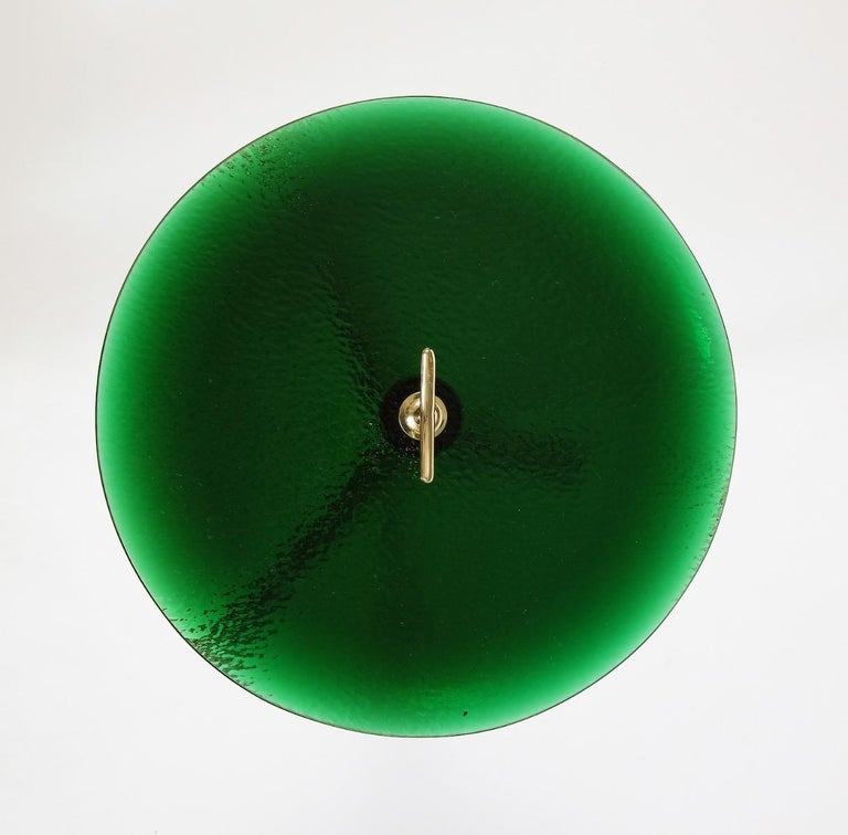Polished brass structure with 3-pronged foot and stylized finial/handle. Thick, circular greenglass table surface with elegant beveled edge & texture underside. Great details throughout.