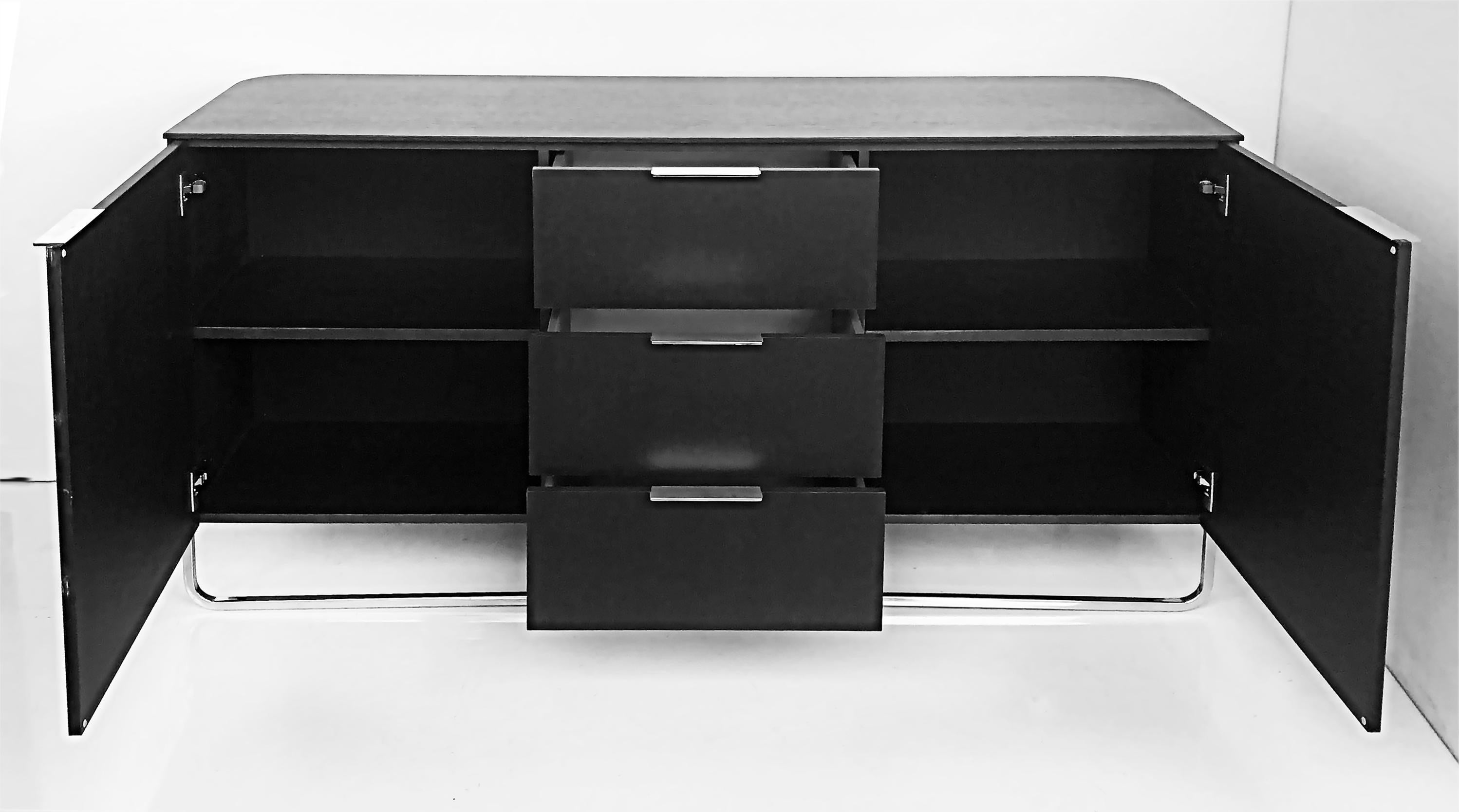 Contemporary Ebonized wood and chrome credenza, 2 doors flanking 3 drawers

Offered for sale is a contemporary ebonized wood and chrome credenza with two lateral doors which open to reveal shelves, flanking three drawers. This piece will work in a