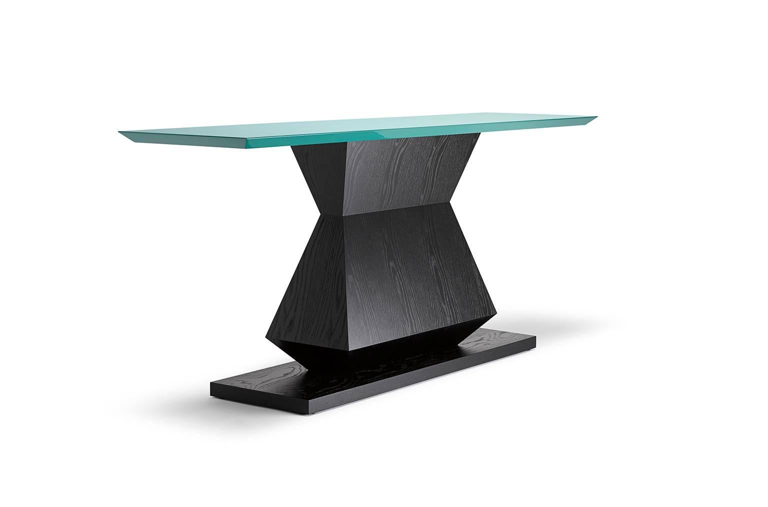 Avec sa base angulaire et symétrique et son plateau biseauté, ce modèle est disponible en tant que console, table d'appoint ou table à manger, avec la possibilité de spécifier une couleur de laque pour le plateau. Montré ici en chêne ébonisé avec un