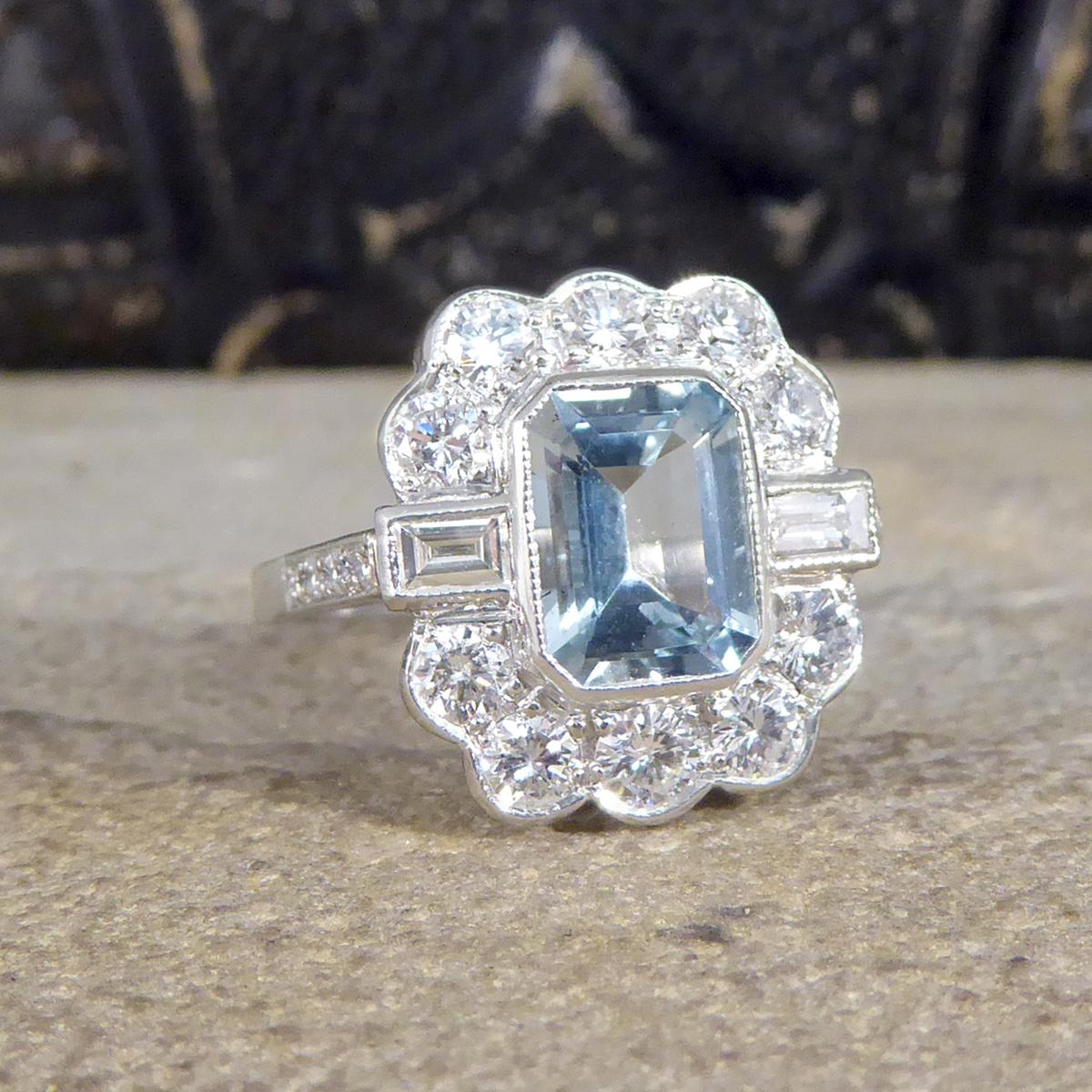 This lovely 1.30ct Emerald cut Aquamarine is surrounded by 5 brilliant cut diamonds along the top and the bottom of the stone with two baguette cut diamonds running horizontal through the middle creating a cluster. The Aquamarine is fairly light in