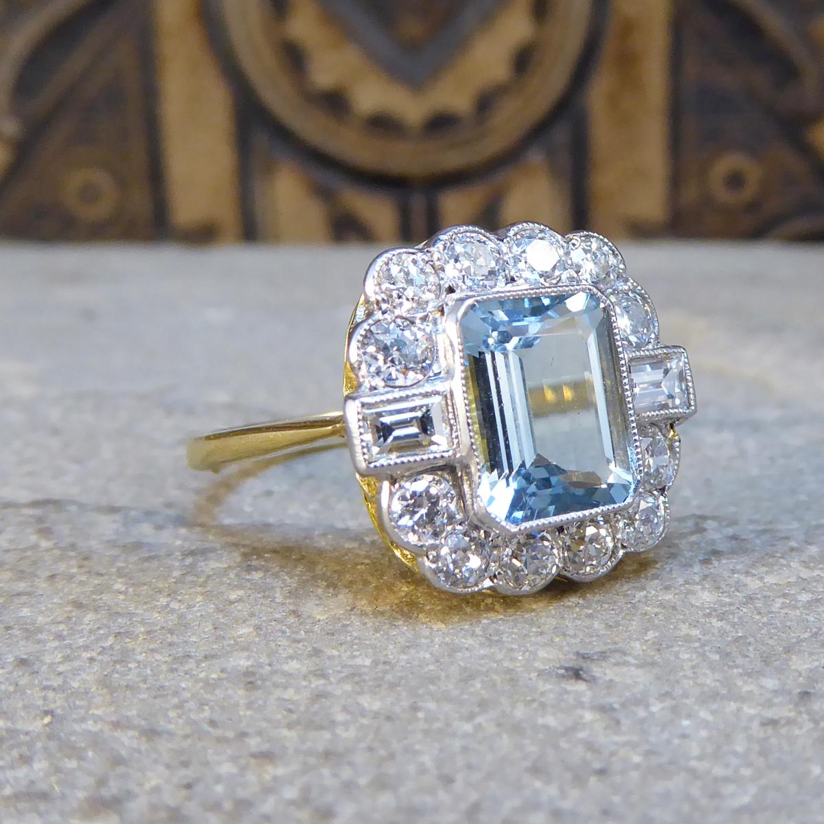 This gorgeous 1.50ct Emerald cut Aquamarine is surrounded by 6 brilliant cut diamonds along the top and bottom of the stone with two baguette cut diamonds running horizontal through the middle creating a cluster. This piece is a contemporary ring