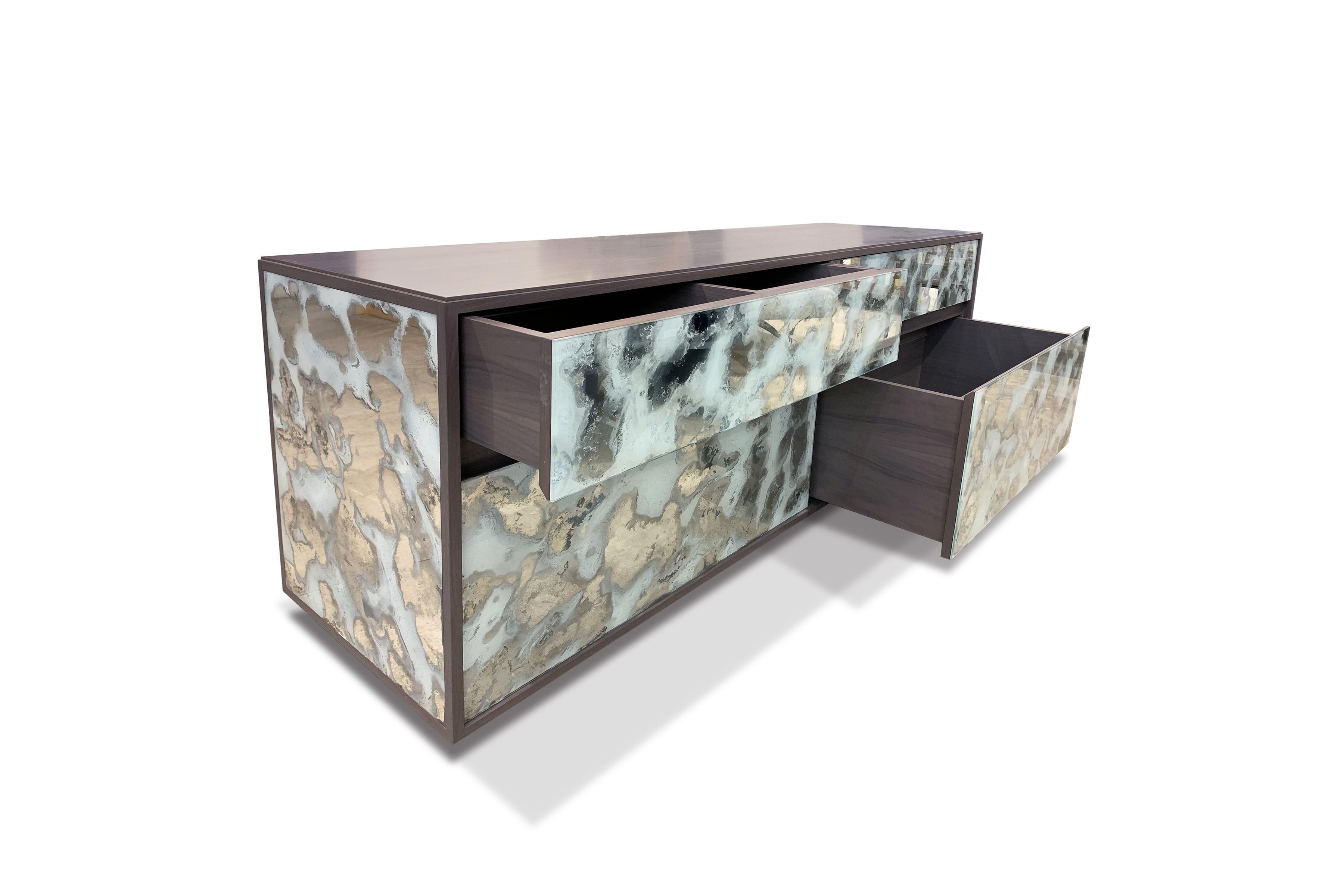 The églomisé white dust chest of drawer / dresser by Ercole Home has a 4-drawer, with stained gray finish on walnut. Hand painted églomisé glass panels are on the surface. Drawers with self-closing hardwares.
Custom sizes and finishes are