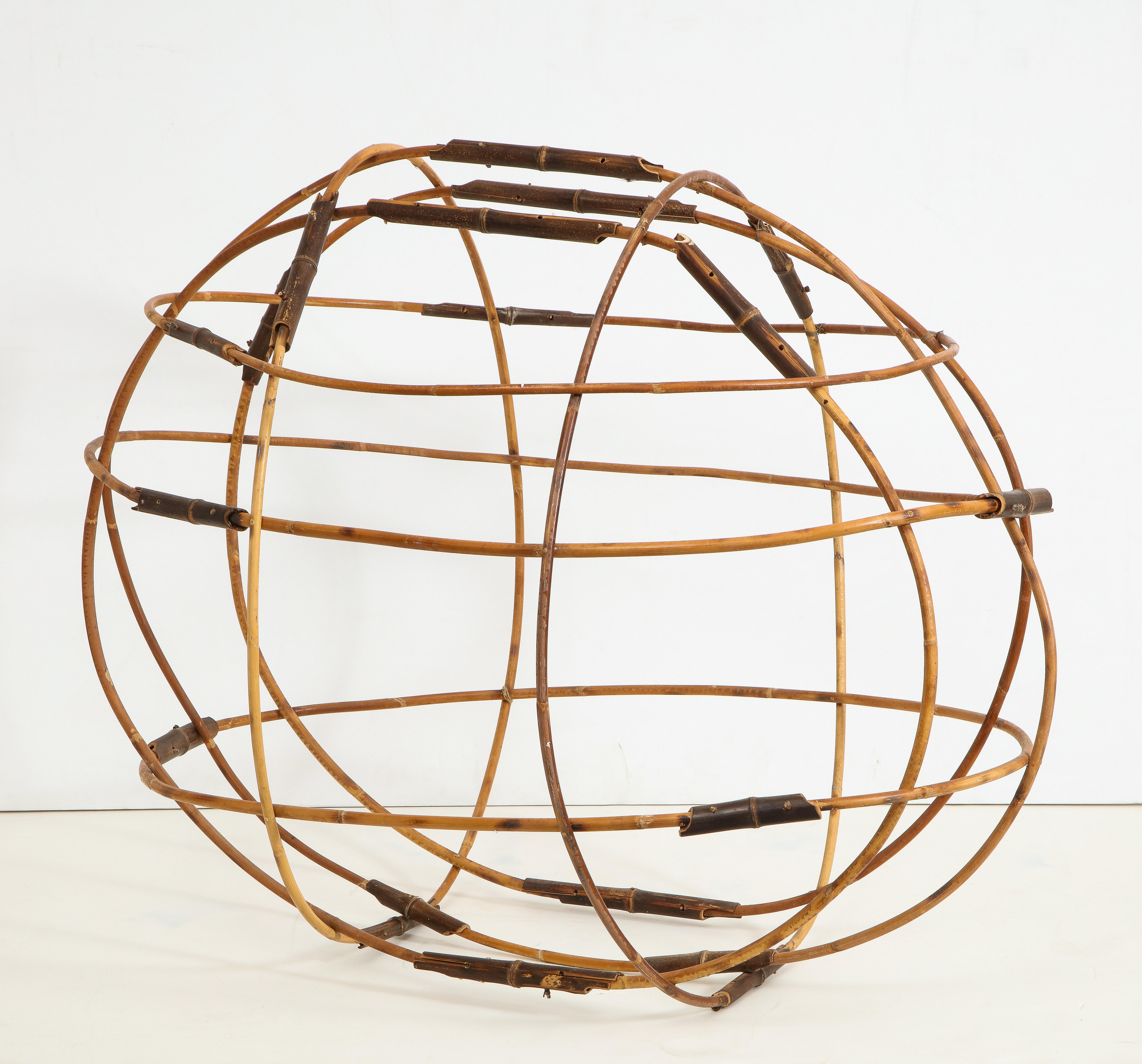 Folk art style oval/elliptical bamboo sculpture, contemporary. Lengths of lighter colored bamboo form the larger ovals with short pieces of darker bamboo accent. Airy and natural.