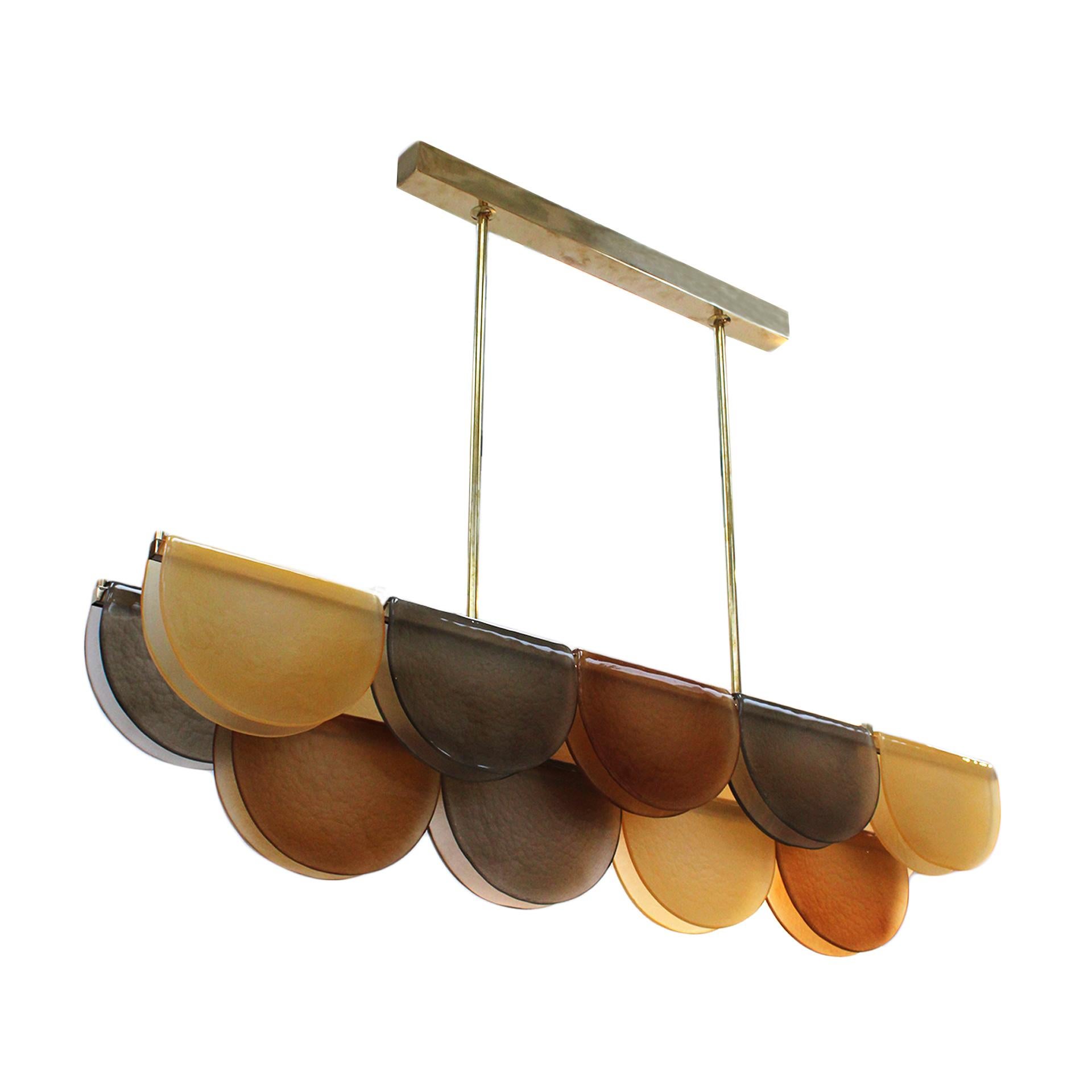 Langgestreckte Hängeleuchte aus einer dreistufigen Messingstruktur, die von LED-Streifen über die gesamte Länge beleuchtet wird. Jede Ebene ist mit einer Murano-Glasplatte umhüllt, die einen gefalteten Effekt um die Struktur herum erzeugt.
Alle