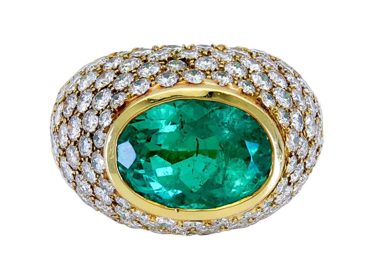 Contemporary Emerald and diamond dome ring. Featuring an faceted oval shaped natural emerald, with classic Colombian color that weighs approximately 6cts. Bezel set horizontally in 18k yellow gold and accented with approximately 4.50 cts of clean