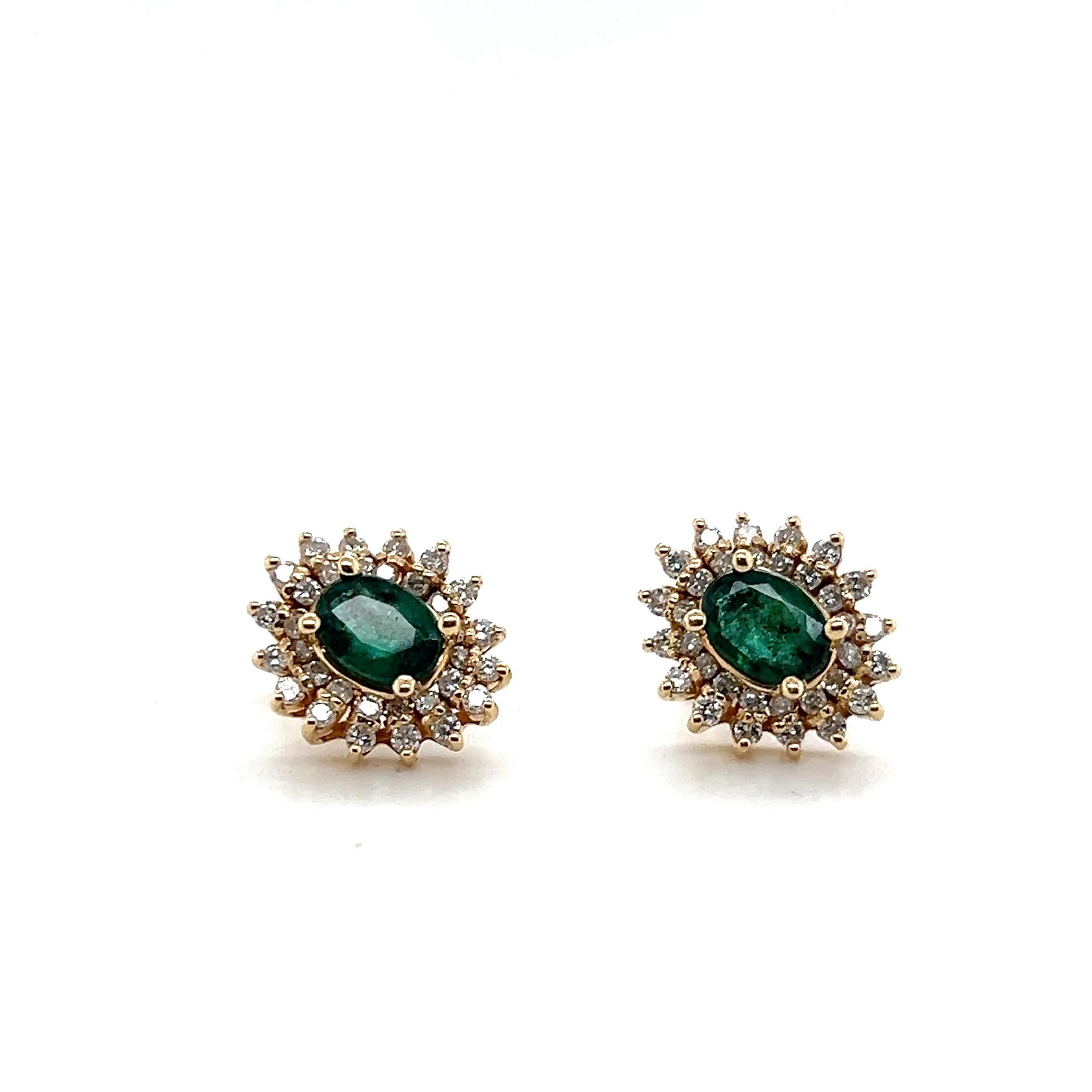 Questo paio di orecchini a grappolo in oro giallo 14 carati presenta due smeraldi ovali per un totale di circa 1,27 carati. Gli smeraldi sono circondati da sessantaquattro diamanti tondi brillanti, per un totale di circa 0,96 carati, con colore I/J