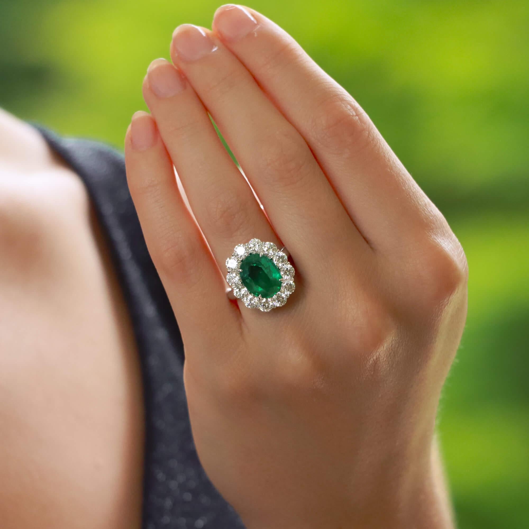 A truly stunning emerald and diamond cluster ring set in platinum.

The piece is centrally set with an astounding 4.33 carat oval cut emerald which is four claw set. The emerald has a fantastic vibrant green colour to it and is surrounded by a