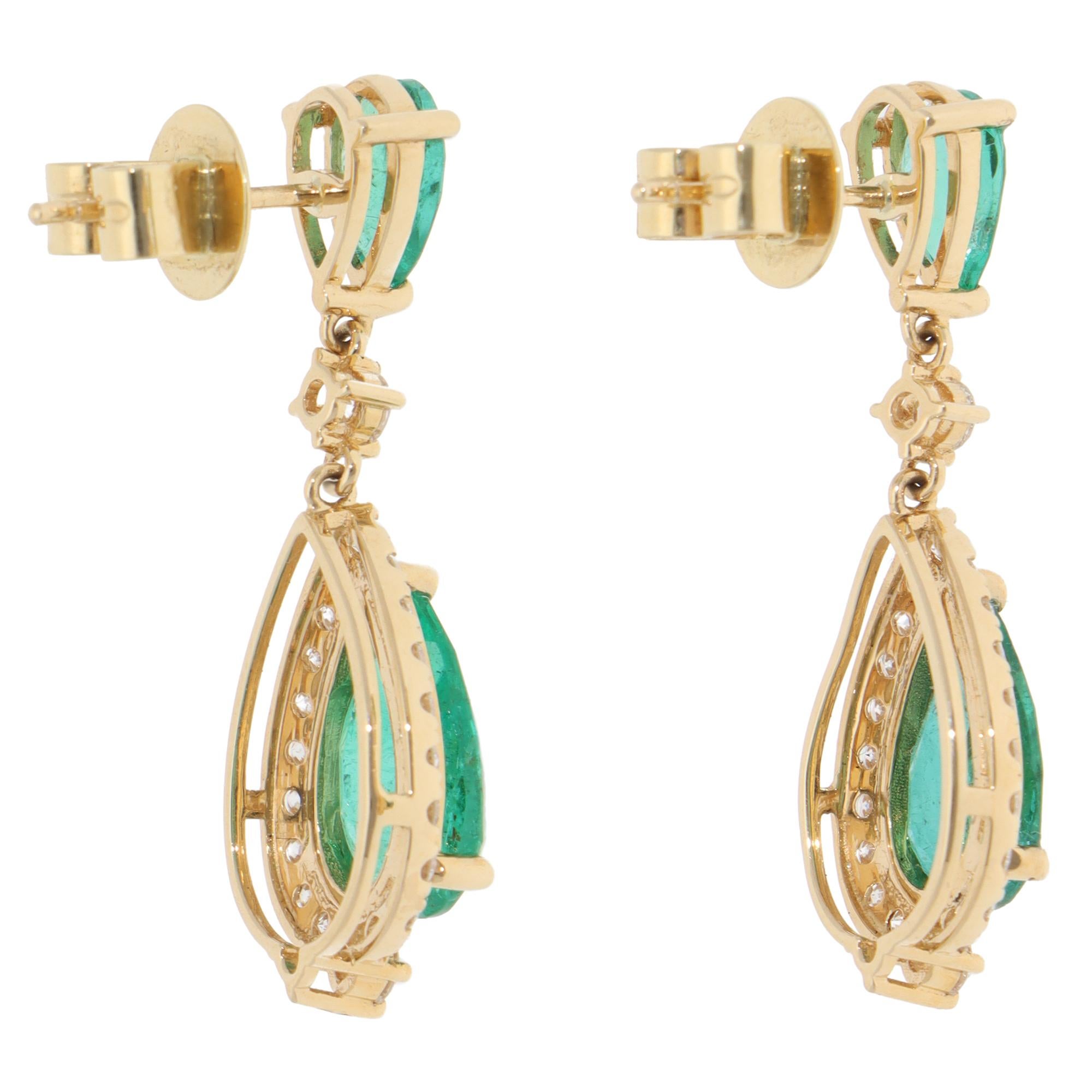 A beautiful contemporary pair of emerald and diamond drop earrings set in 18k yellow gold.

Each earring is firstly composed of a pear cut emerald stone, three claw set securely and fitted with a post and butterfly back. Hanging from the emerald is