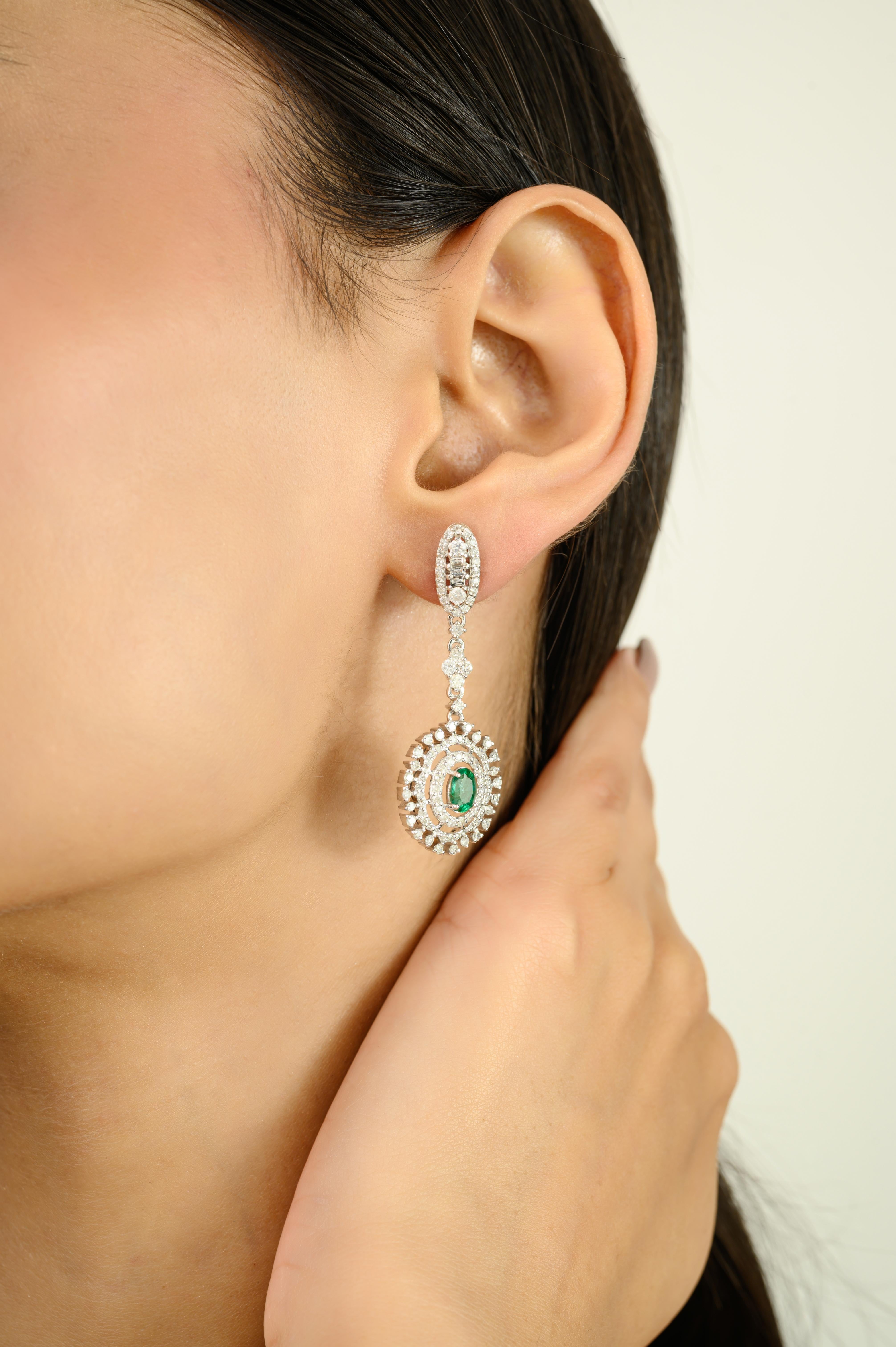 Indulge in timeless elegance with these Contemporary Emerald and Diamond Floral Drop Earrings finely crafted in 14K gold. Featuring a total diamond weight of 2.08 carats, these earrings shimmer with exceptional brilliance, perfectly complemented by