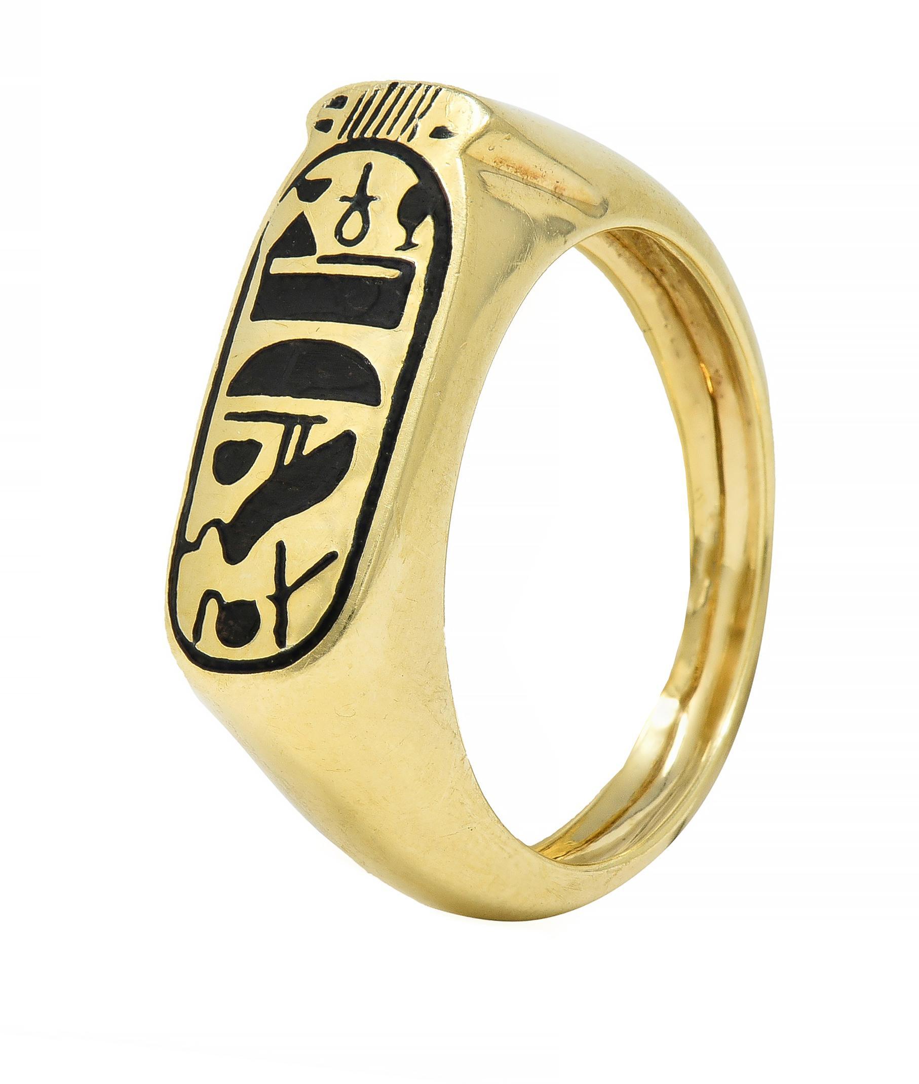 Designed as a slim cartouche shape featuring champlevé enamel hieroglyphics
Depicting a bird, anch, bowl, and other forms with linear surround 
Completed by rounded shoulders 
With high polish finish
Stamped for 14 karat gold
With maker's mark