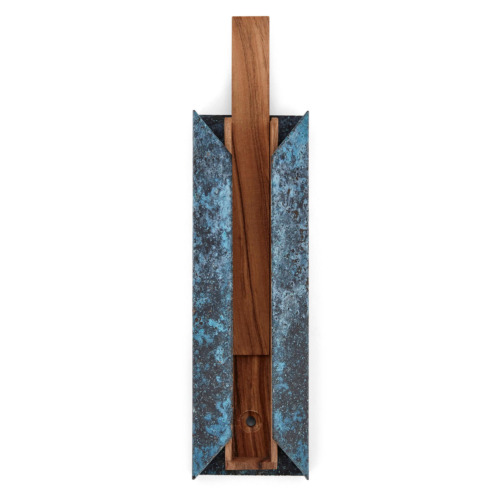 This elegant and sculptural mezuzah in sterling silver, olive wood and copper is inspired by what a home represents. Named ‘House’ mezuzah by the artist, the form voices protection. The highly polished sterling silver cylinder made to contain the