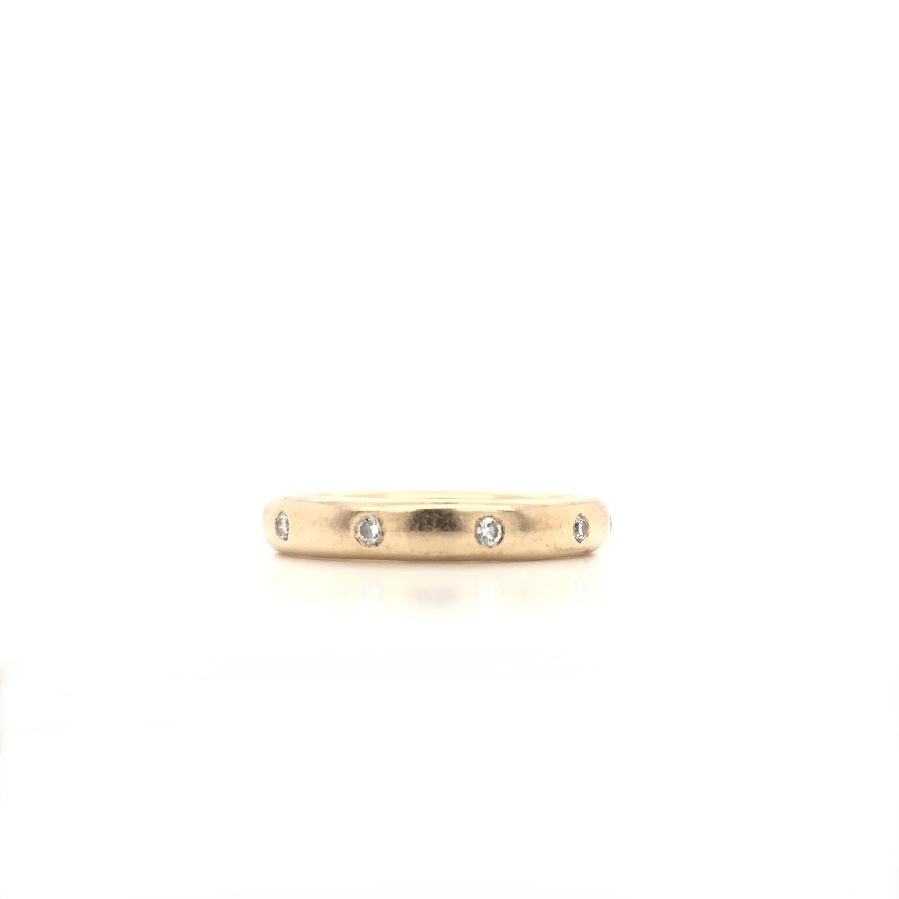 This contemporary estate 14K gold band features 10 tiny sparkling flush set diamonds. The 10 tiny diamonds encompass the entire length of the band. This modern style would compliment a curated stack of diamond bands or modern wedding set