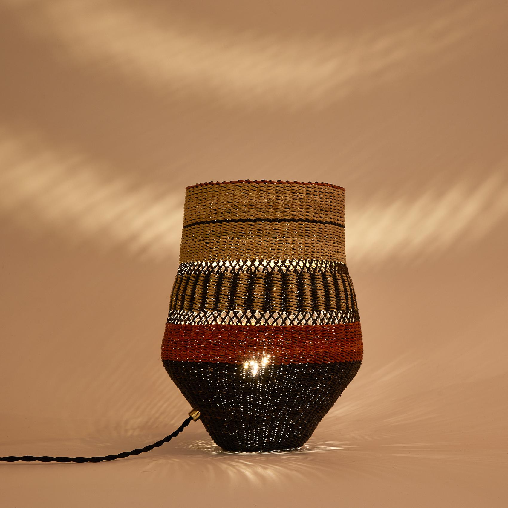 Woven table lamp
Colours: Natural and Black punctuated by an Terracotta

Are you looking for unexpected objects to decorate your home? This base shaped table lamp is delicately woven and will be a funky element in your room (measuring approximately