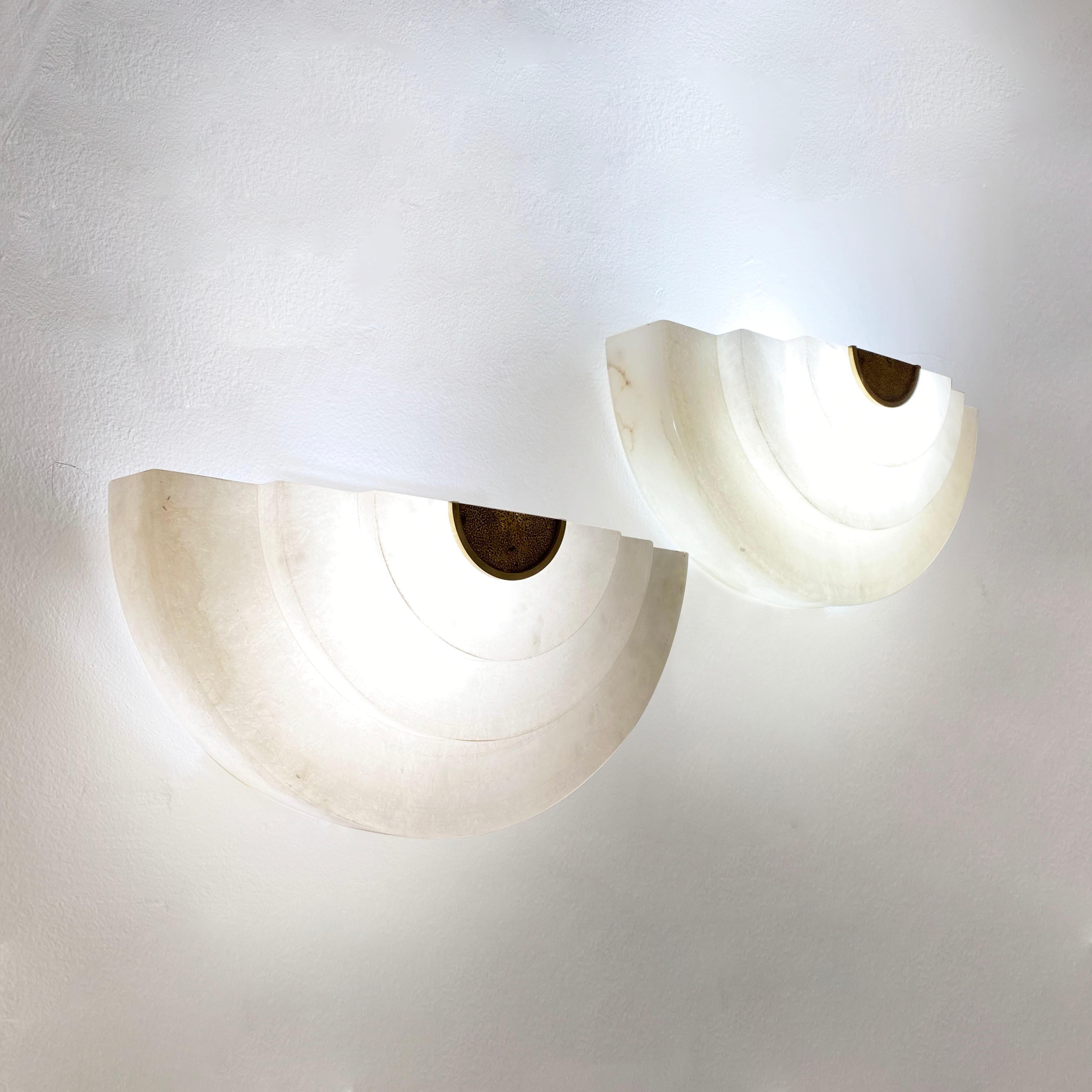 Iconic Art Deco is still here! This contemporary pair of sconces, entirely handcrafted in Spain, has a typical streamlined Art Deco design and reflects the era in all the details: the stepped half-moon organic shape, the use of material with the