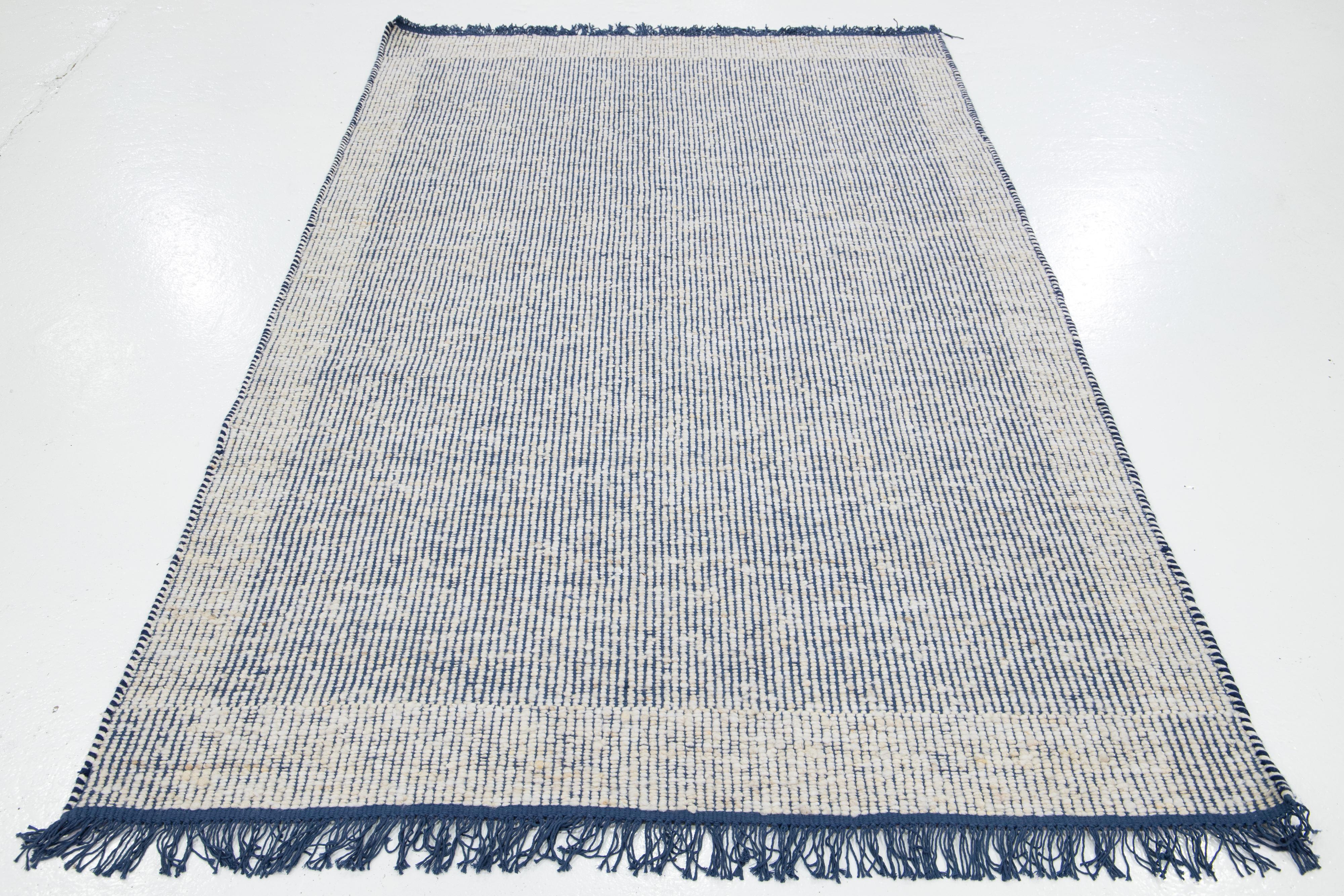 Questo bellissimo tappeto in lana Felt, tessuto a mano, fa parte della nostra Collectional Westport. Ha un campo blu e un disegno geometrico avorio all-over con frange.

Questo tappeto misura 5' x 8'.

Colori e dimensioni personalizzate sono