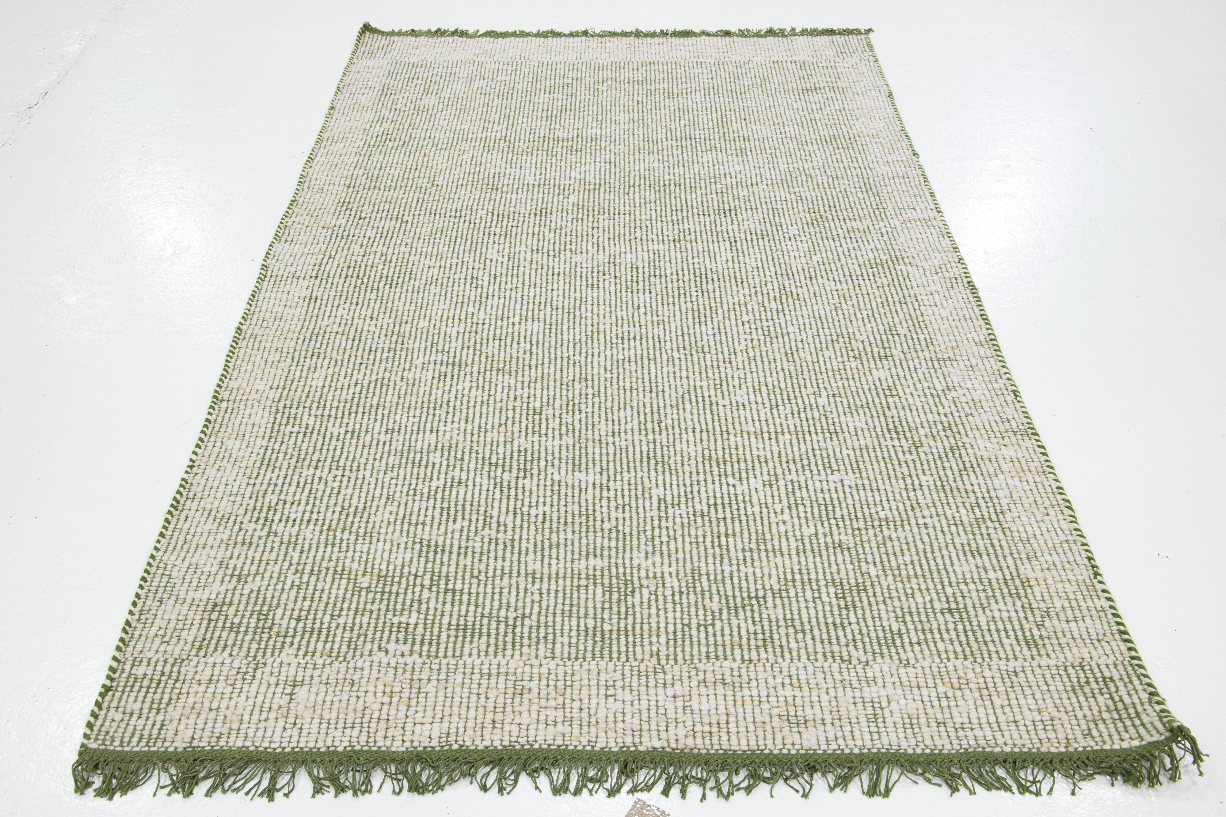 Dieser schöne handgewebte Wollteppich aus Filz ist Teil unserer Westport Collection'S. Es hat ein grünes Feld und ein elfenbeinfarbenes geometrisches Allover-Muster mit Fransen.

Dieser Teppich misst 5' x 8'.

Kundenspezifische Farben und Größen
