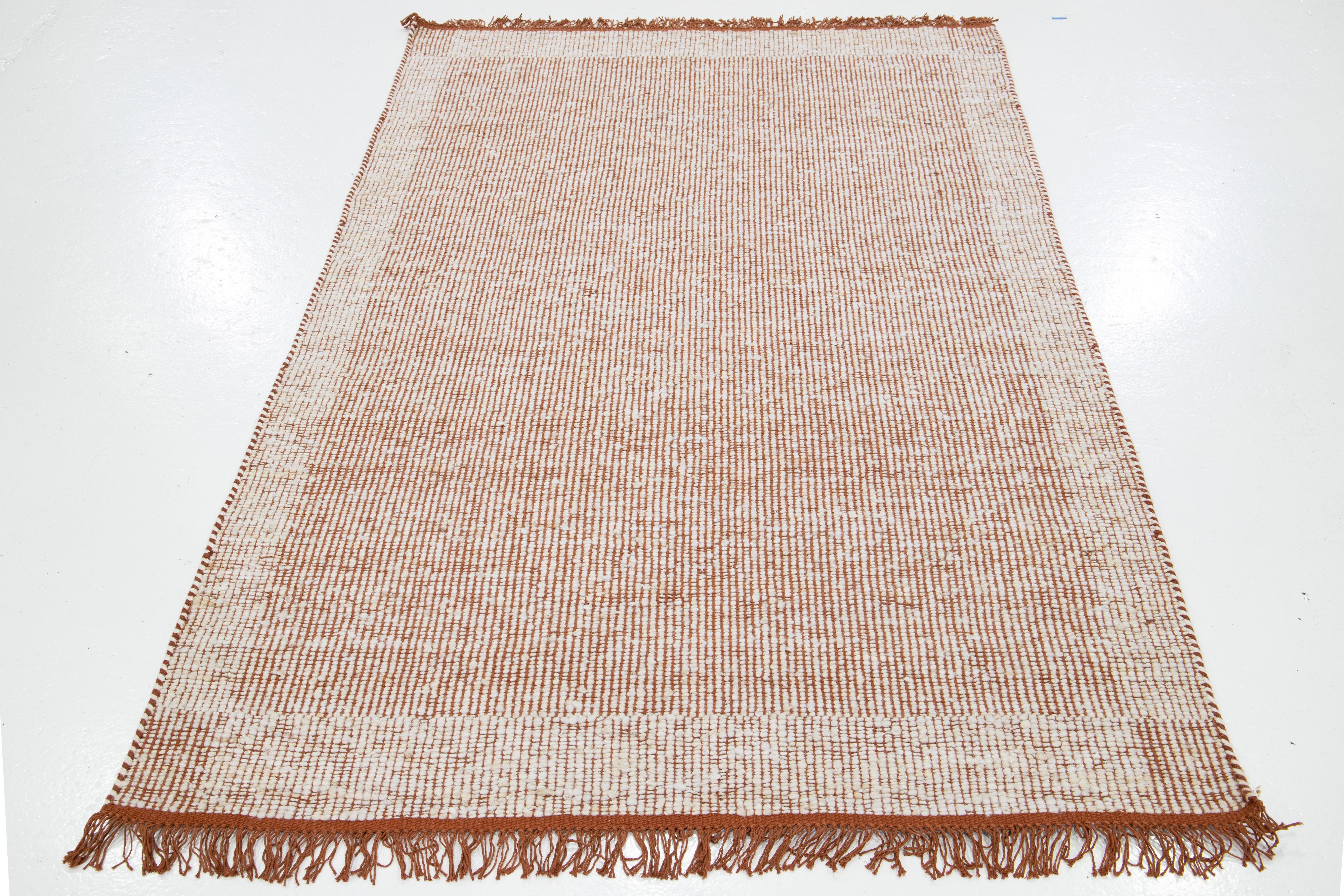 Ce magnifique tapis en laine Felt tissé à la main fait partie de notre Collection Westport. Il présente un fond rouille et un motif géométrique ivoire avec des franges.

Ce tapis mesure 5' x 8'.

Des couleurs et des tailles personnalisées sont