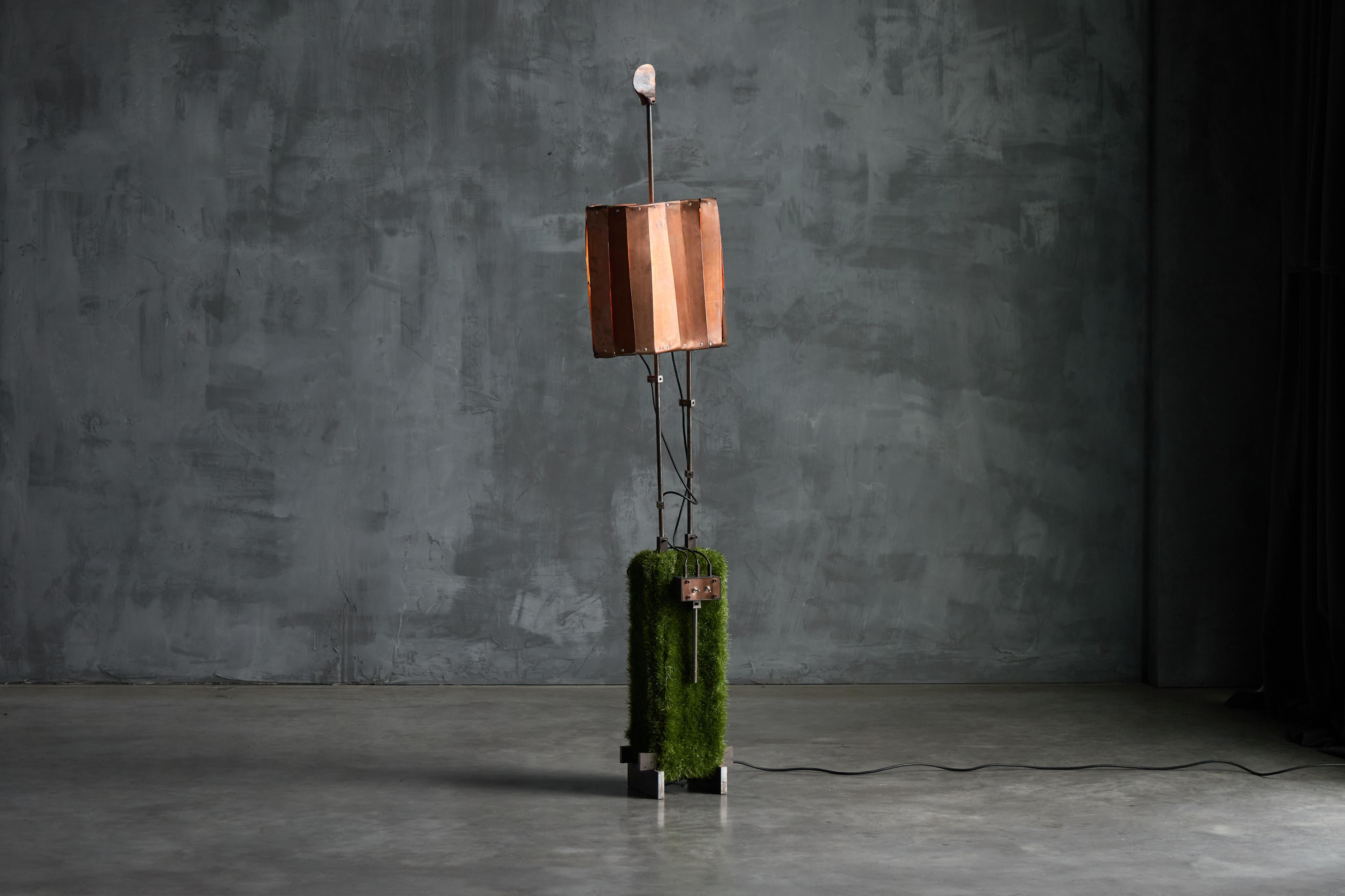 Floor lamp by Thomas Serruys, a striking contemporary design that combines raw industrial elements with organic textures. The lamp features a tall, sculptural composition with a copper-toned shade, delicate metal framework, and a base covered in