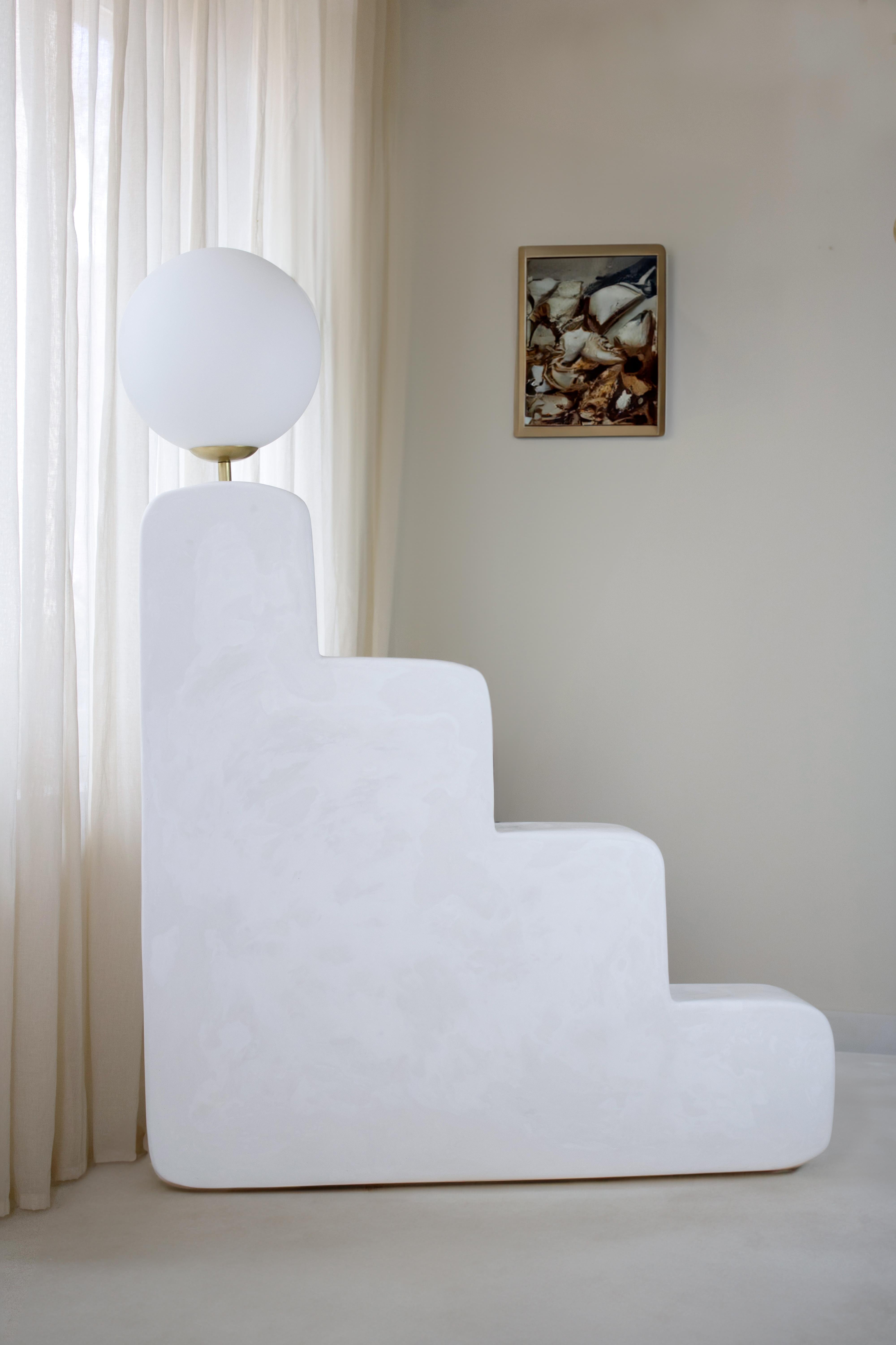 Big Step Lamp is a contemporary handmade lamp from the Forms Collection, made in gypsum. The sculpture’s form alludes to ambition and enlightenment in a playful way. The lamp’s smooth, organic curves invites the viewer to explore its surface with