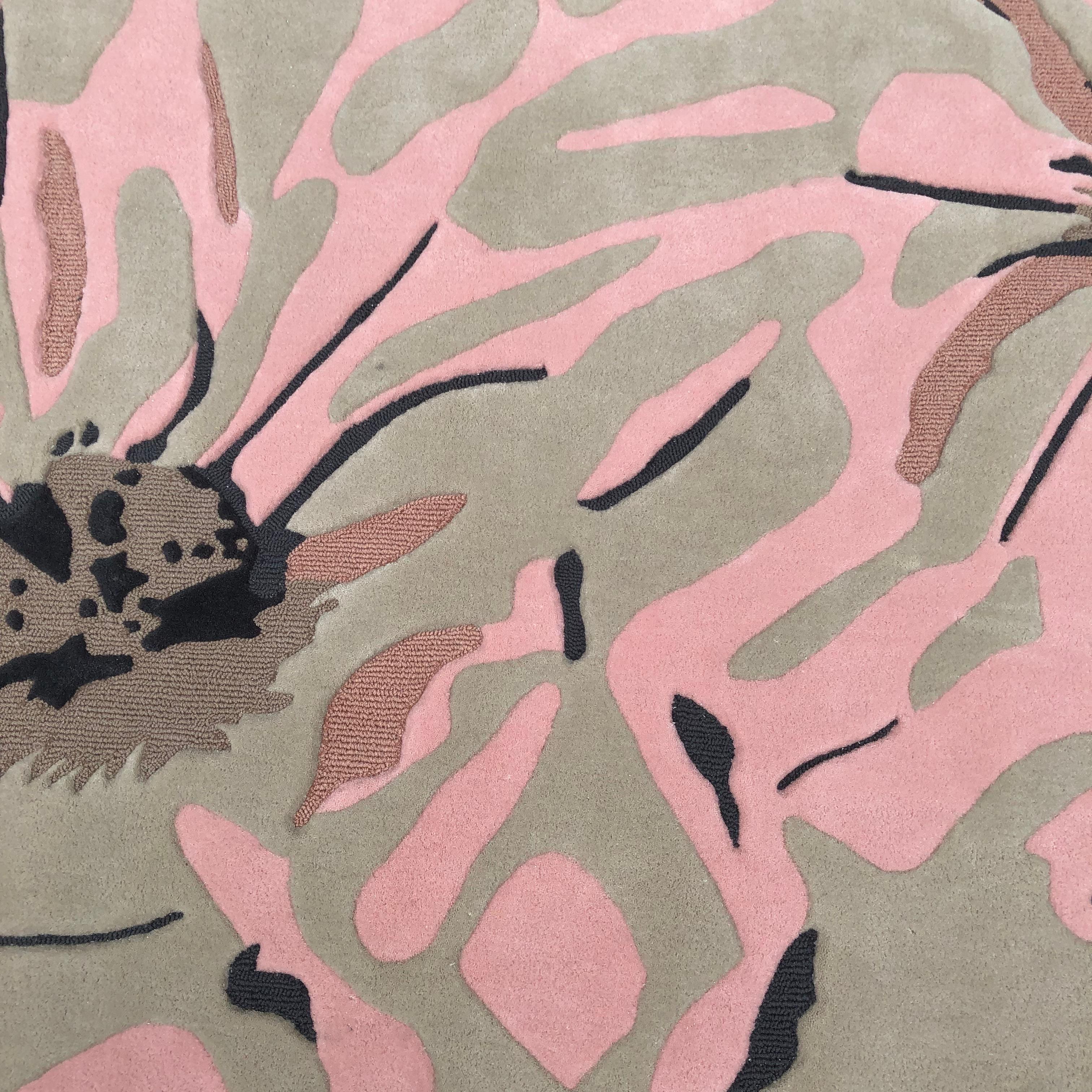 A bold contemporary rug inspired by the organic beauty of blooming flowers. Featuring oversized abstract petals in soft pink, grey, and taupe with deep navy accents, it creates a striking visual centerpiece. The sculpted, free-form silhouette