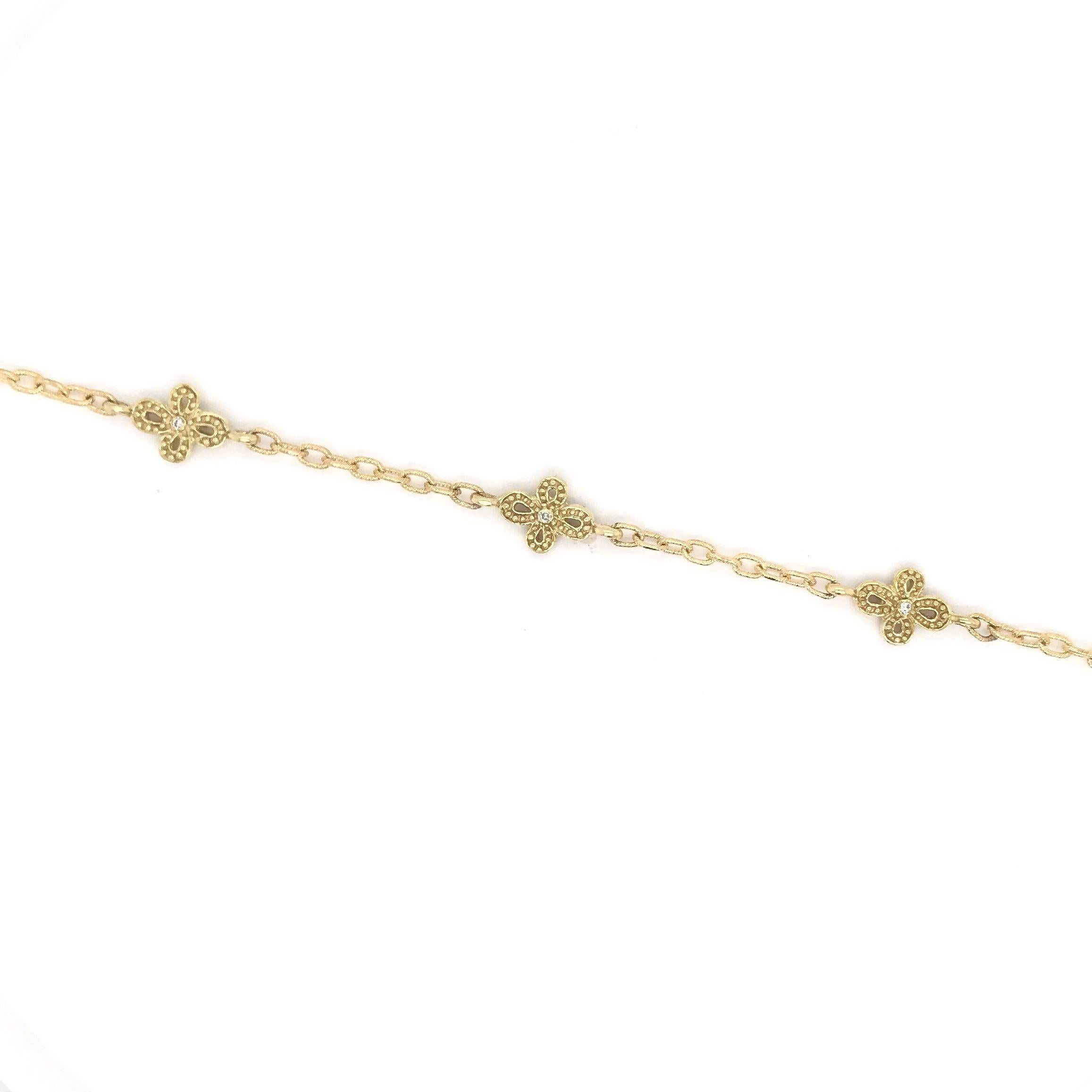 This dainty 18K gold diamond bracelet is a contemporary piece. Each of the five charms resemble a small flower with a tiny sparkling diamond in the center. The links feature fine textured details. This bracelet currently measures approximately 8