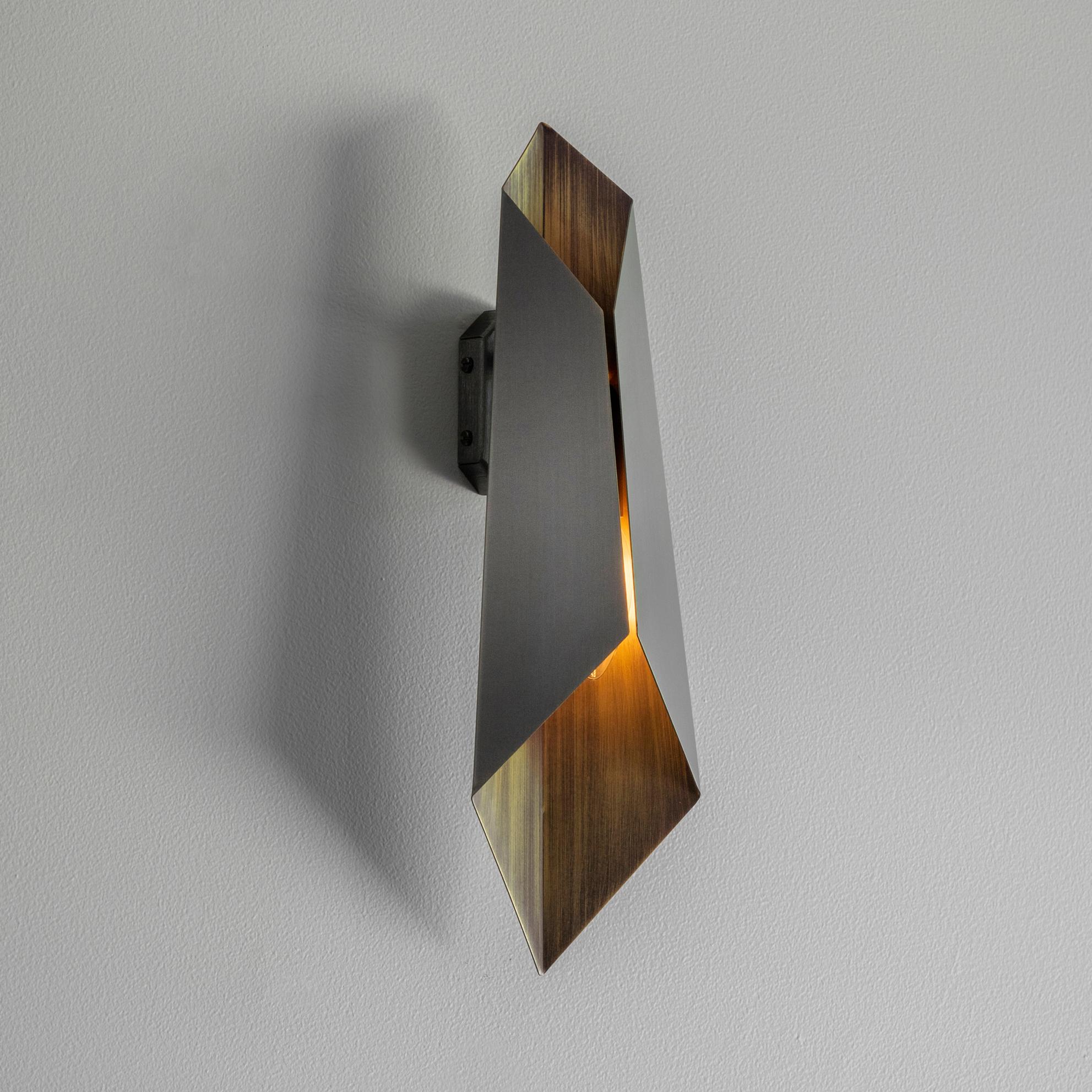 A folded bronze wall light, patinated to a dark bronze colour and hand-grained on the inside surface to reflect the light. Use singly or group together for impact.

Designed and handmade by Tigermoth Lighting on the banks of the river Thames in