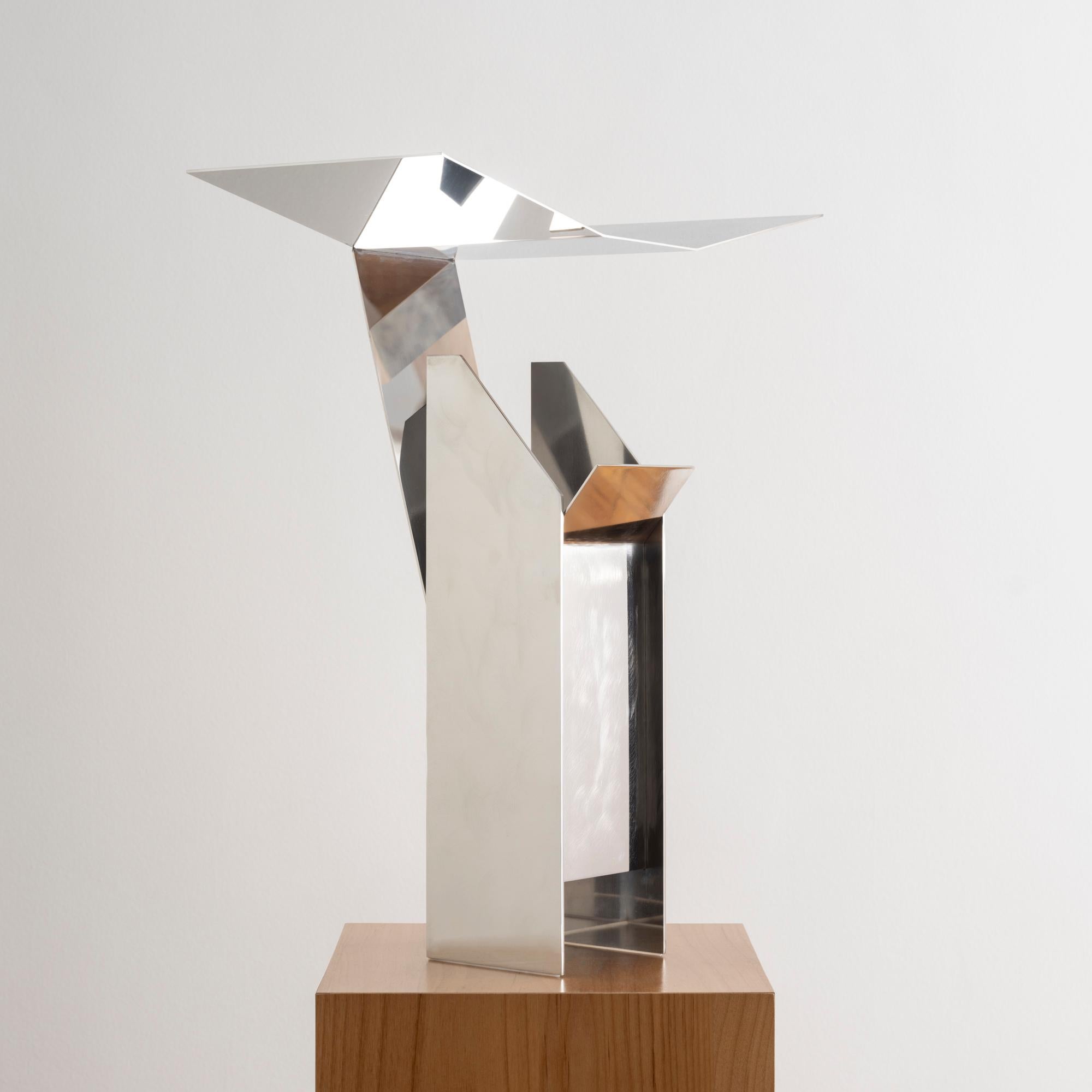 Designed by EJR Barnes in 2023, this contemporary stainless steel table lamp is sculpturally bent into an angular shape to artfully reflect and diffuse light beneath a folded metal canopy. 

Entitled 