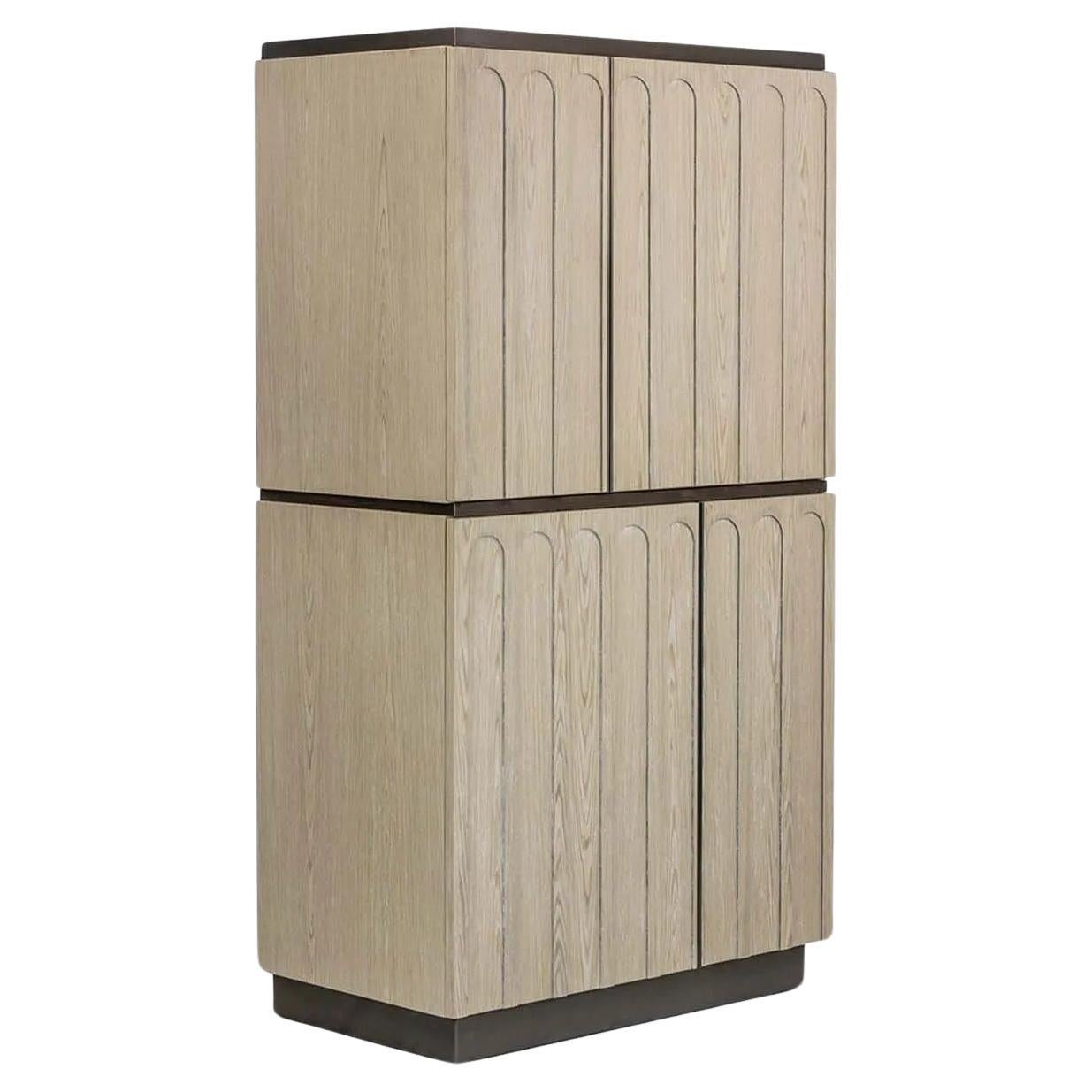 A four-door cabinet with an asymmetrical and dynamic design featuring varying-sized doors arranged with purposeful intent. The embossed archways on the door faces add a touch of texture and detail to its artful composition. The base and details in
