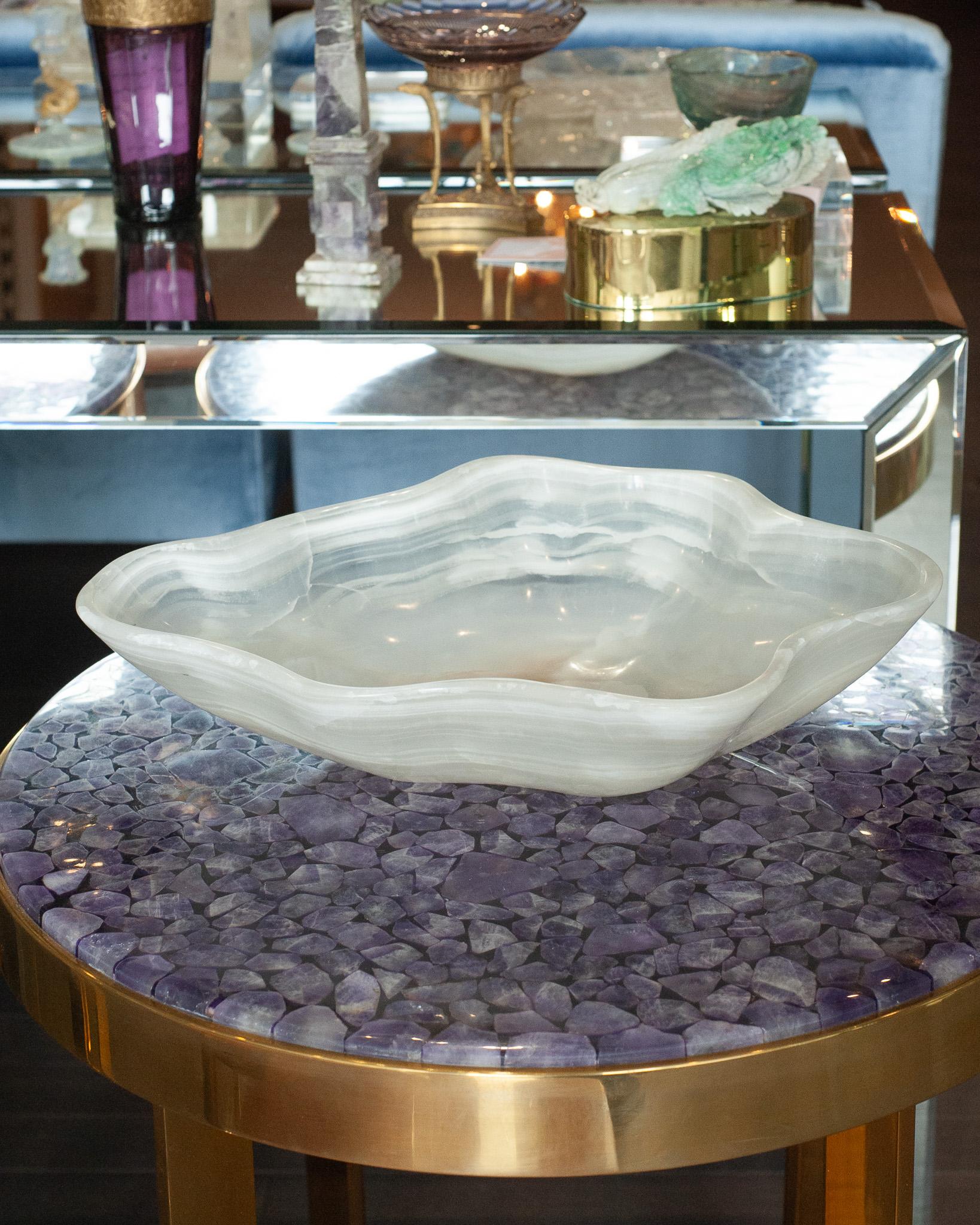 Invite the healing energy of onyx into your home with this remarkable, hand-carved mineral bowl. Crafted from a single piece of onyx, the bowl showcases banding in opaque and translucent white. Its highly polished finish gives the surface a glossy