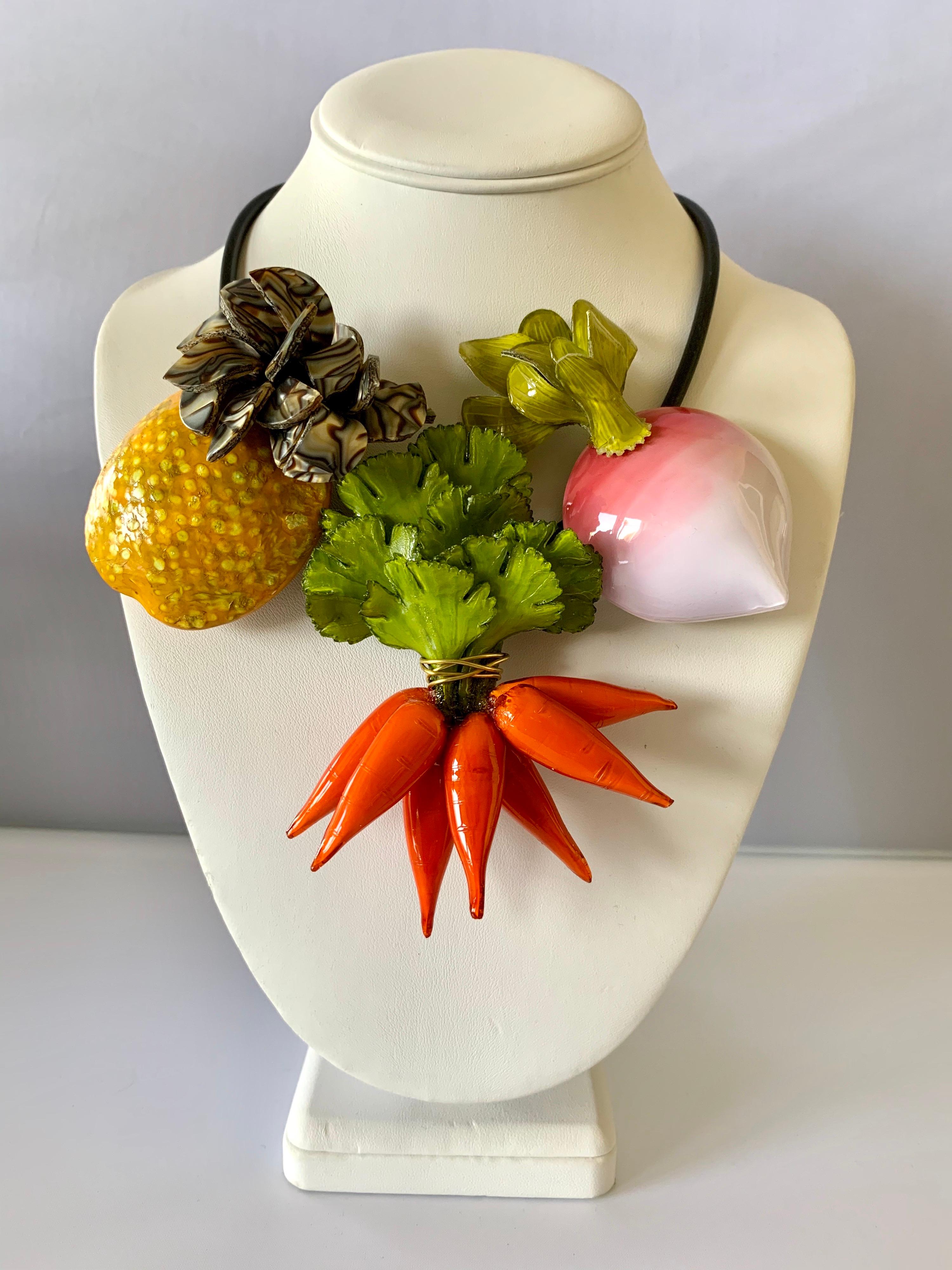 Contemporary French designer fruit and vegetable statement necklace - the statement necklace is comprised out of a black rubber cord that is embellished by a pineapple, carrot, and radish pins. The piece can be worn as a necklace or the items