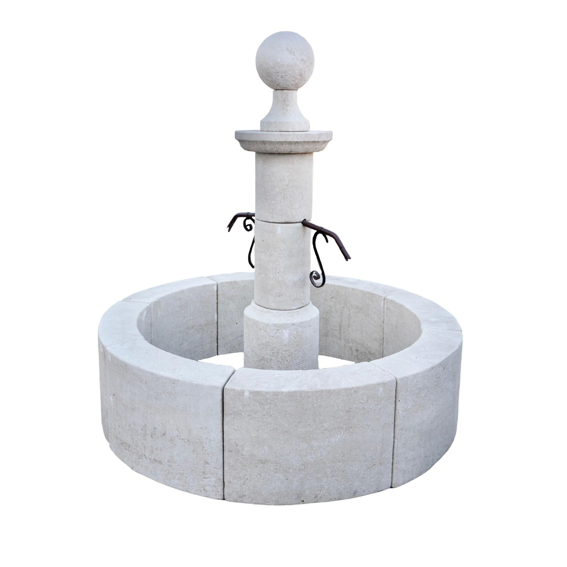 Fontaine française de style central, taillée à la main dans la pierre calcaire, avec un bassin circulaire qui permet un débordement généreux de l'eau à partir des points de sortie. Au centre du bassin se trouve un pilier avec deux trous pré-percés