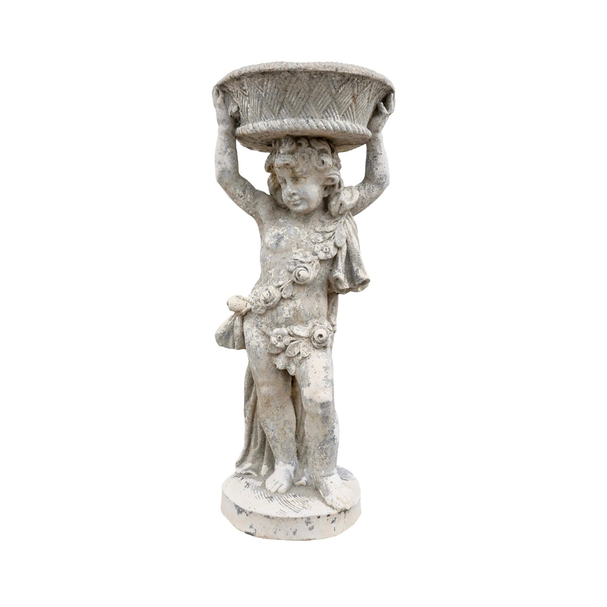 This contemporary French limestone putti sculpture planter is a beautiful addition to any garden or indoor space. The sculpture features a putti holding a basket above its head, which can be used as a planter. Made from a durable concrete composite,