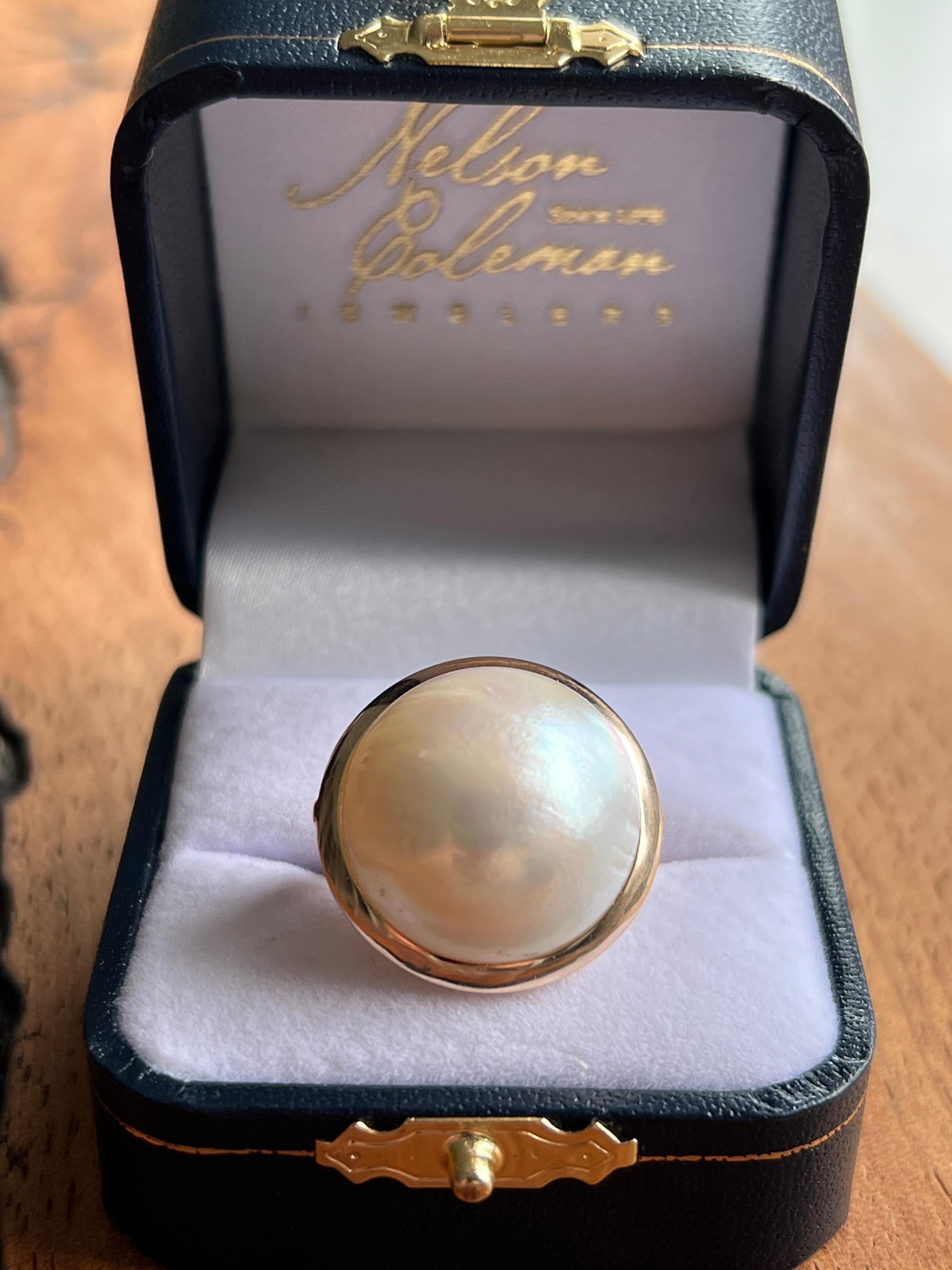Un anello contemporaneo in oro giallo 14 carati con un'imponente perla di acqua dolce coltivata a bottone di 19,5 mm. La perla luminosa è splendidamente esposta in una cornice audace con un'altezza della testa di 14,88 mm, che conferisce al design