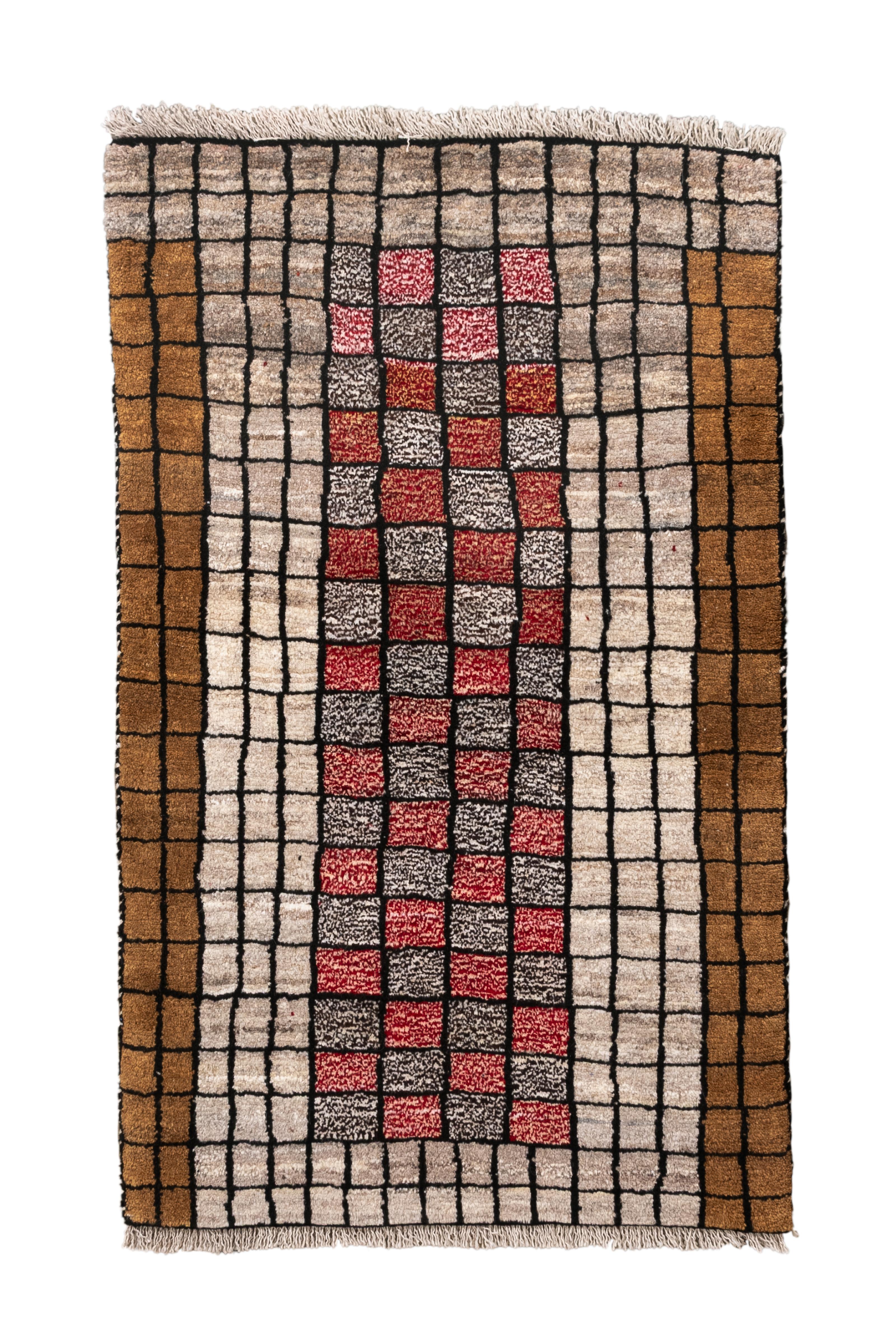 This modern Gabbeh rug, measuring 2′7″ × 4′2″, features a bold and graphic checkerboard design. The central vertical column is composed of alternating squares in red, charcoal, and ivory, set against a neutral grid with warm caramel brown and taupe