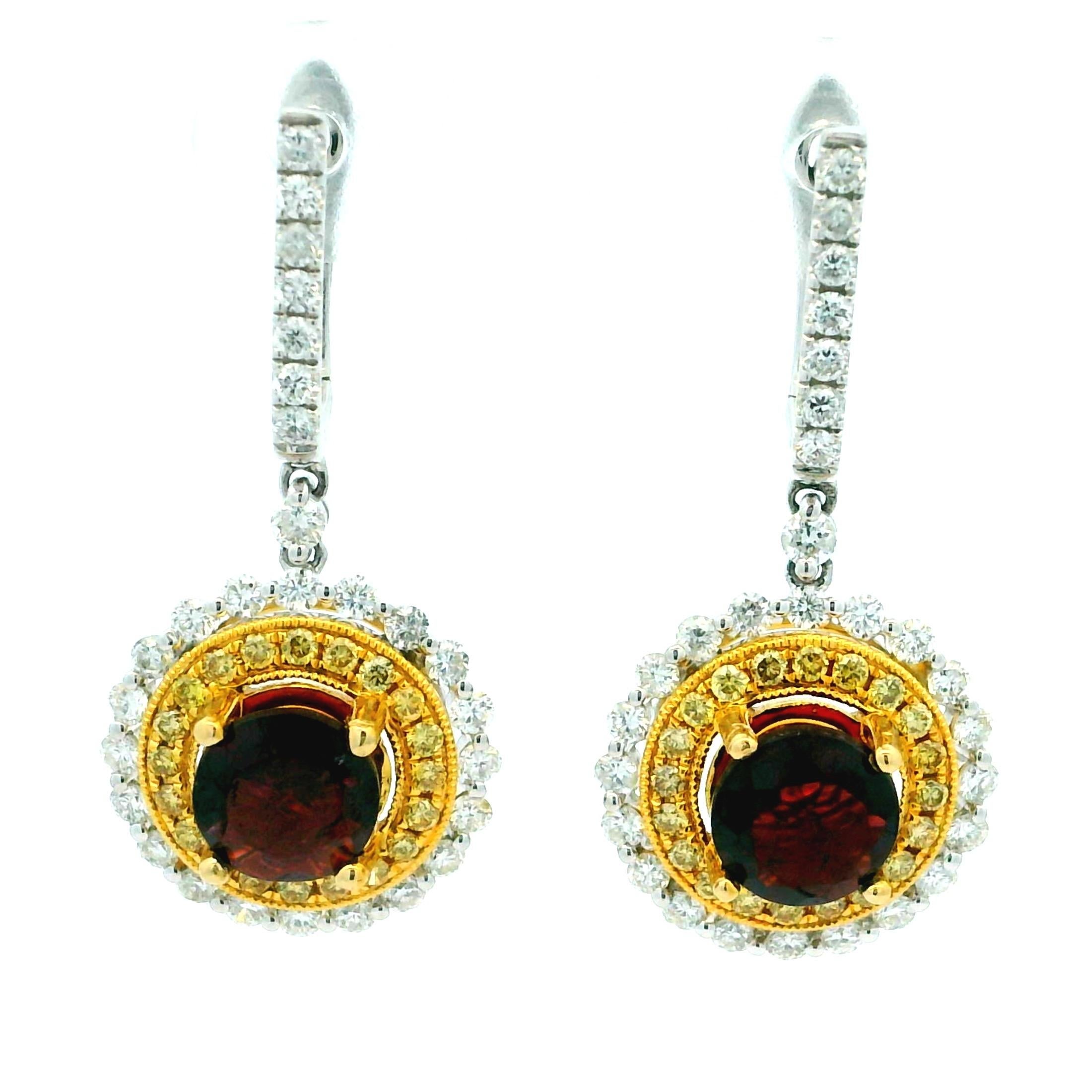 Ein auffallendes Paar moderner Tropfenohrringe mit tief weinroten, runden Granaten, eingefasst in warmes 14-karätiges Gelbgold und umringt von zwei Halos aus funkelnden Diamanten. Der innere gelbe Diamantenkranz sorgt für einen warmen Farbton,