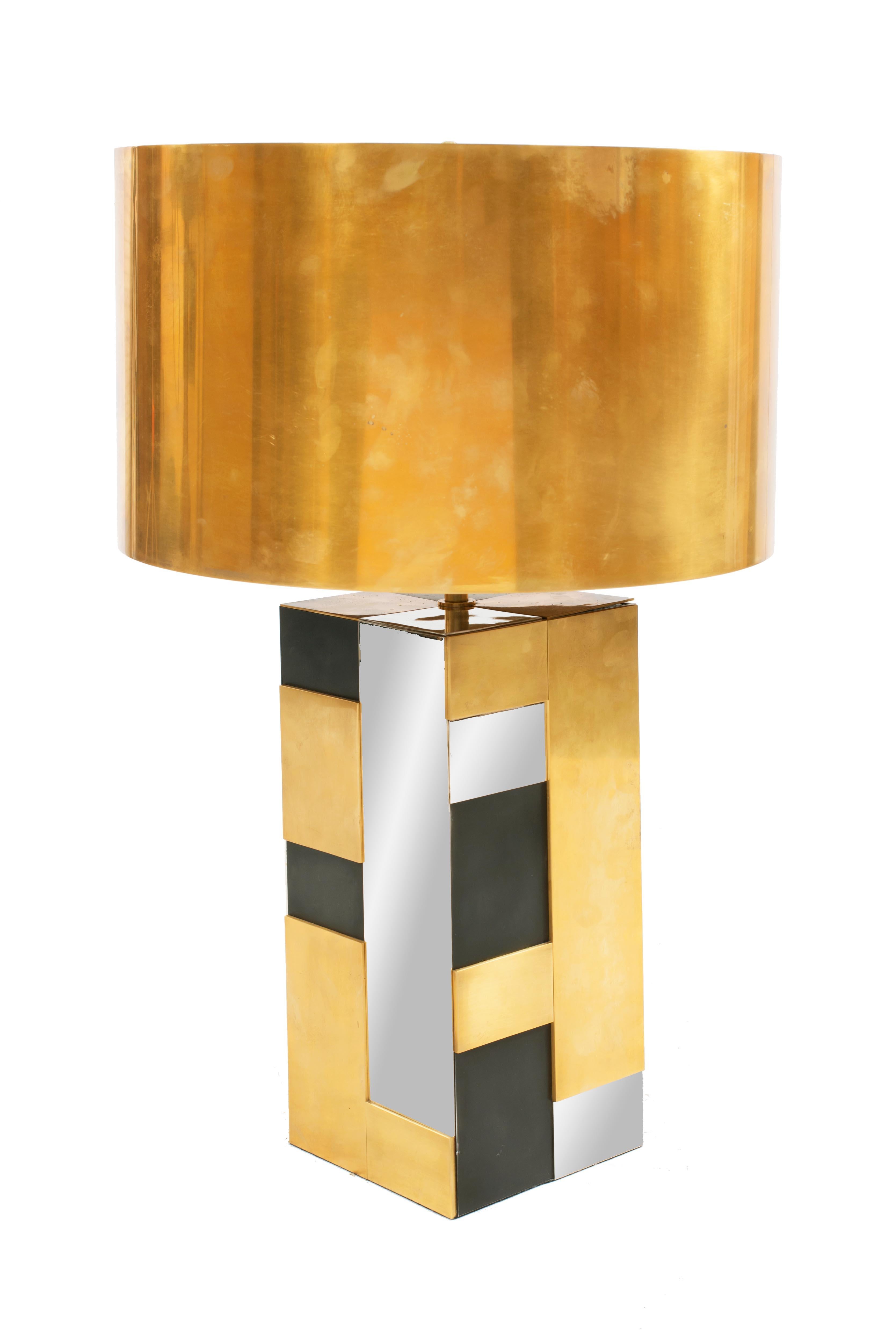Contemporary brass, bronze, polished nickel, and black metal table lamp with faceted square detail & a burnished brass drum shade.
     