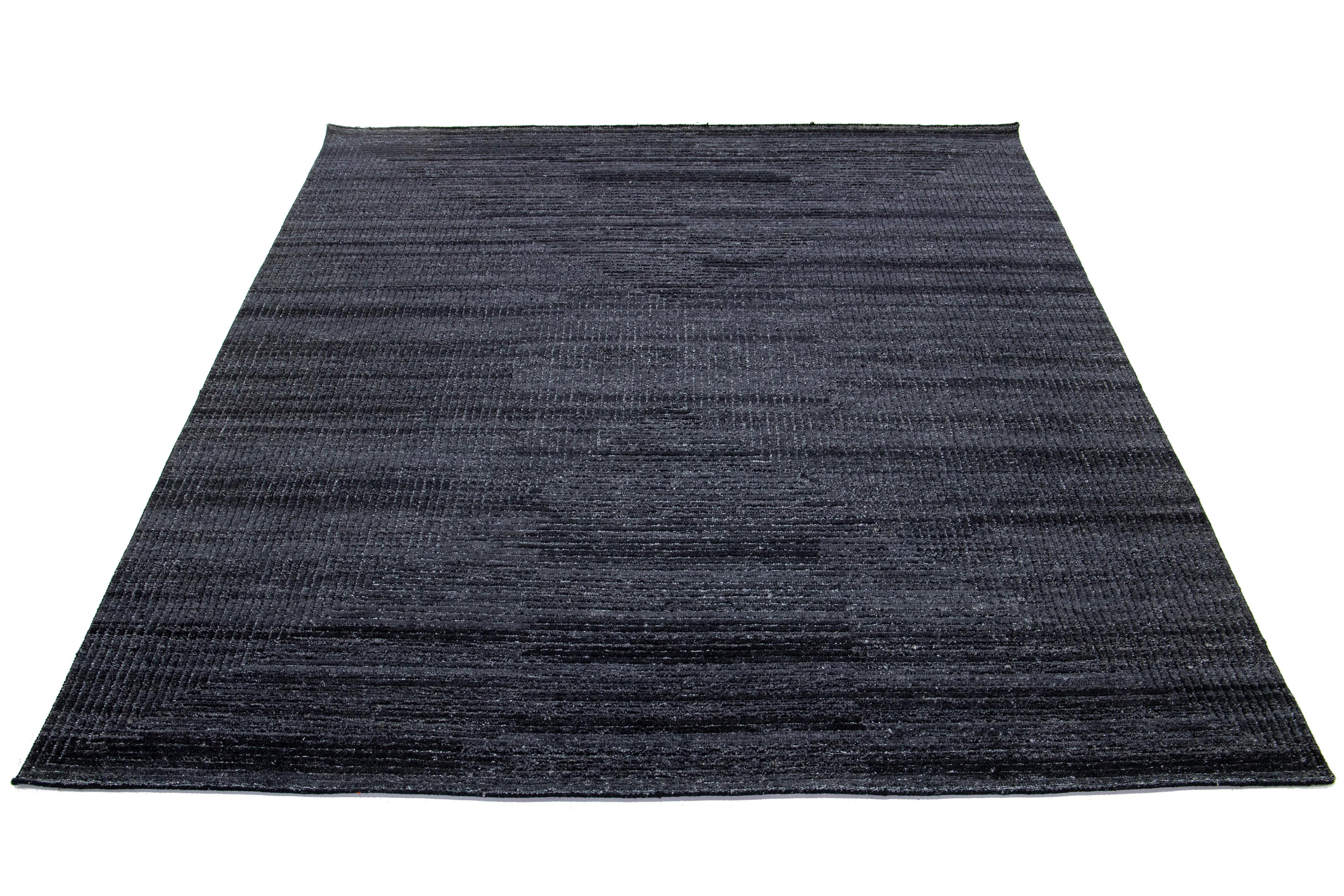 This handmade Moroccan wool rug showcases an Organic Modern style with a geometric design in shades of charcoal gray.

This rug measures 8'1