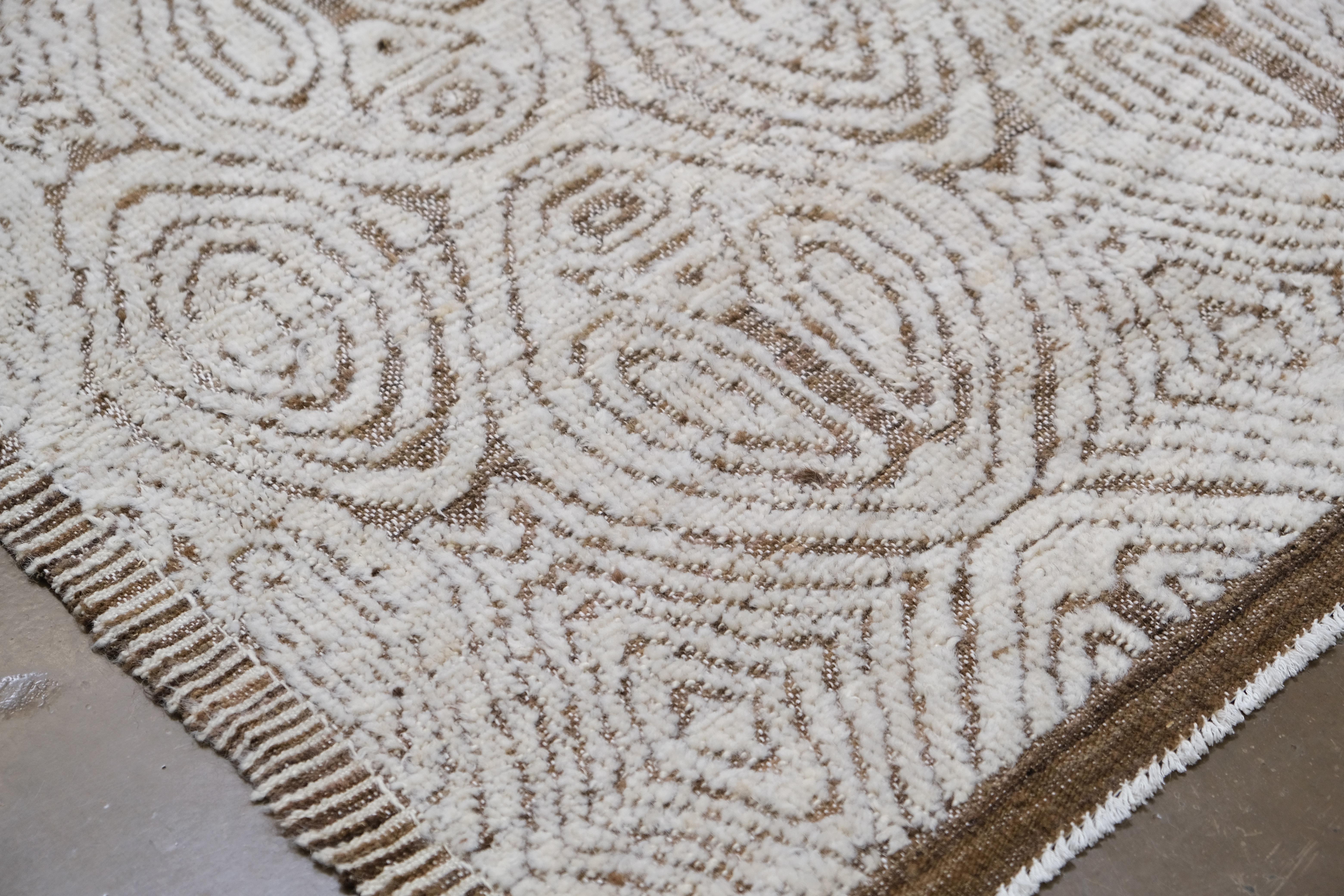 Esta exquisita alfombra de lana anudada a mano es una auténtica obra maestra de artesanía y diseño moderno. Con unas medidas aproximadas de 3 x 4 m, la alfombra presenta un intrincado patrón geométrico de motivos ovales repetidos, tejidos a mano con