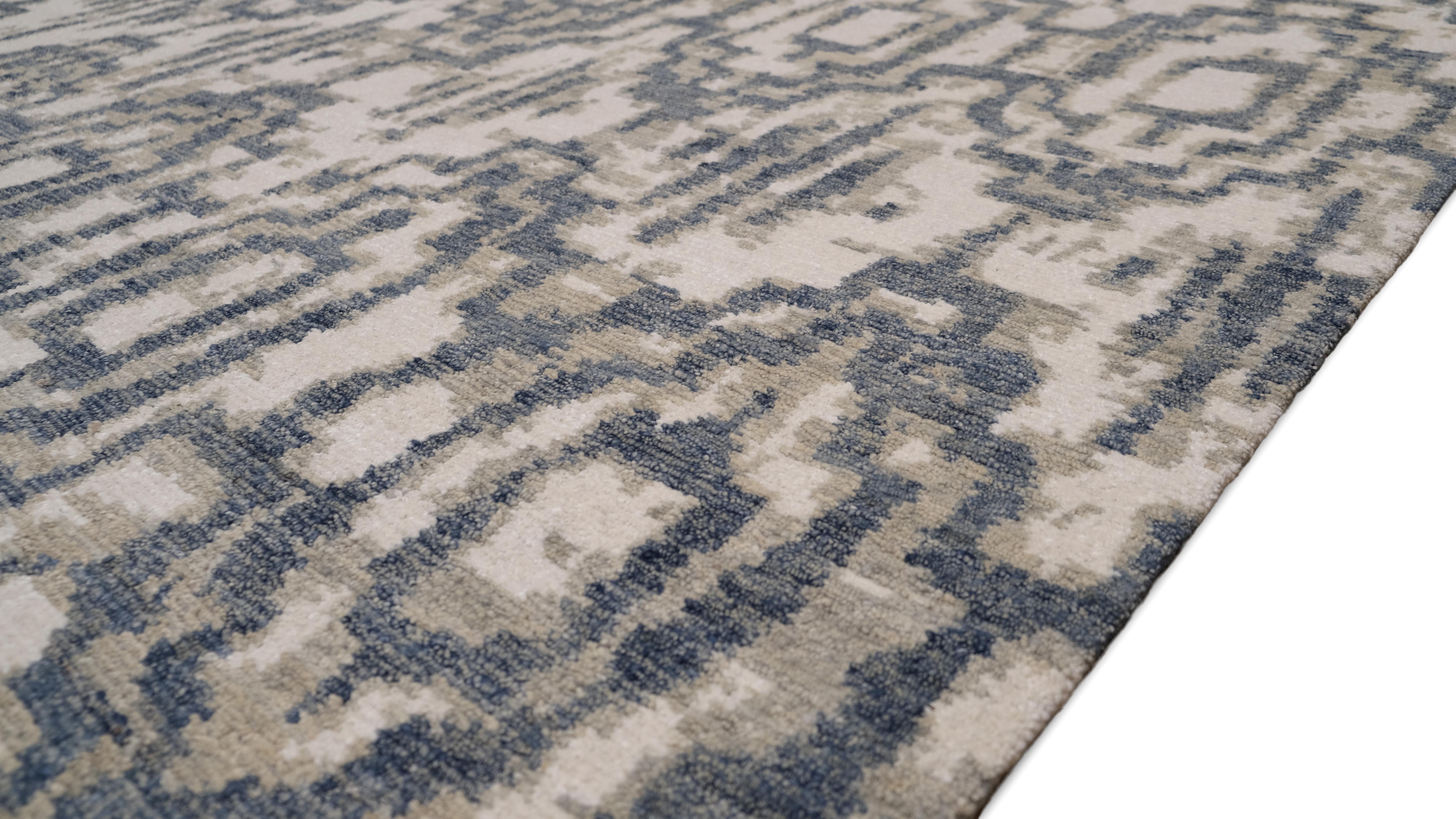 Introduce una mezcla de sofisticación moderna y artesanía con esta alfombra de lana anudada a mano. Con un intrincado estampado geométrico en tonos azules, verdes y marfil suave, esta alfombra añade profundidad y textura a cualquier espacio