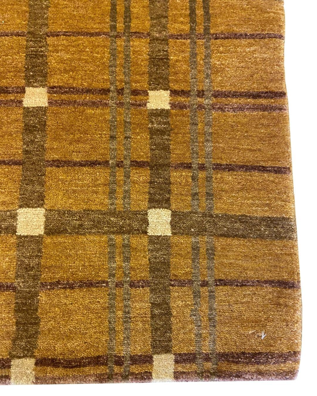 Dieser 2′ × 3' große, handgeknüpfte Wollteppich verbindet traditionelle Handwerkskunst mit einer klaren, modernistischen Sensibilität. Das Design zeichnet sich durch einen warmen goldbraunen Grund aus, der von einem Gitter aus sich kreuzenden Linien