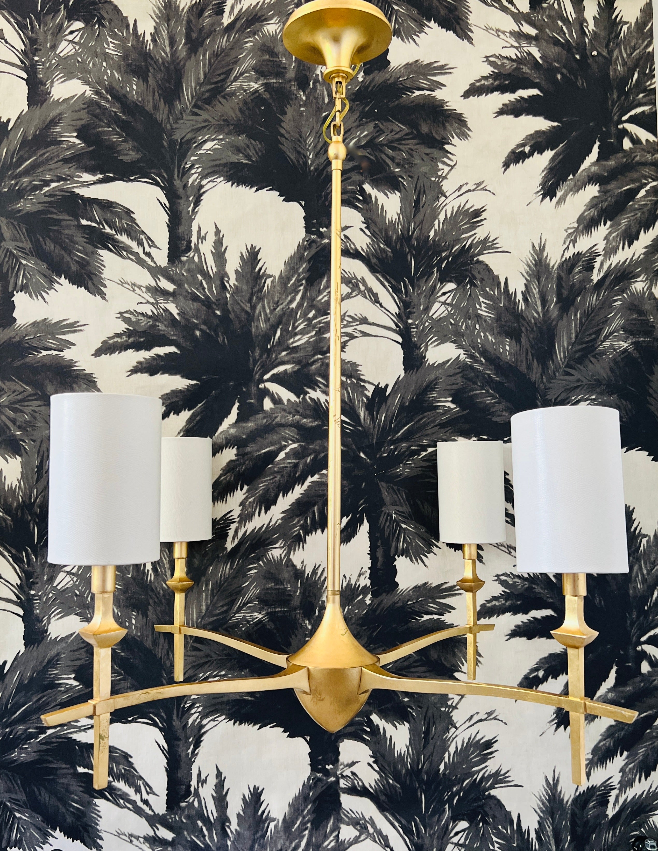 Contemporary gold leaf chandelier with four arm design. The stylized frame has curved arms, candelabra lights, and custom shades in ivory with an embossed snakeskin pattern. Hollywood Regency design with Neoclassical elements. 

36