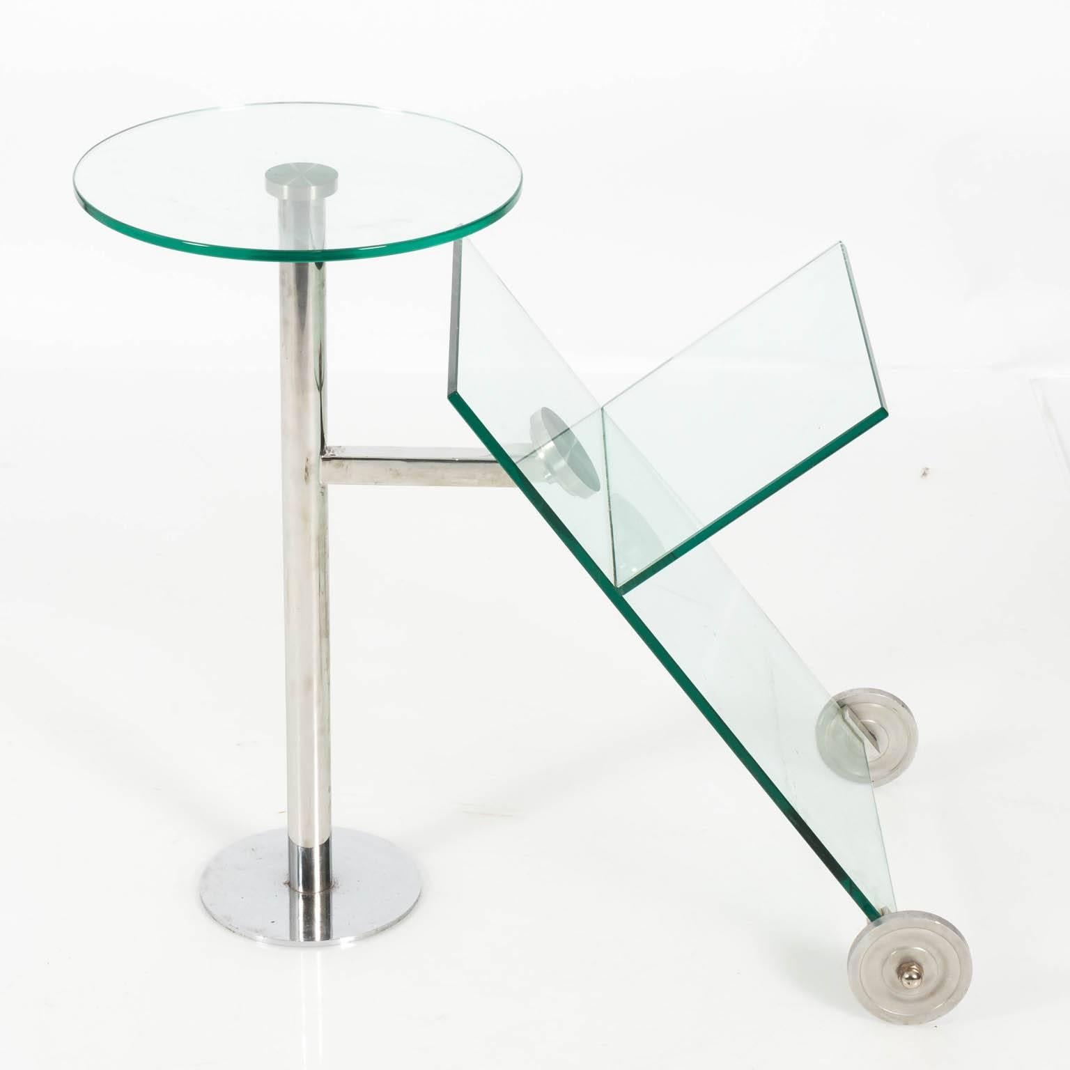 Contemporary glass and chrome base magazine stand in a polished finish on wheels.
 
