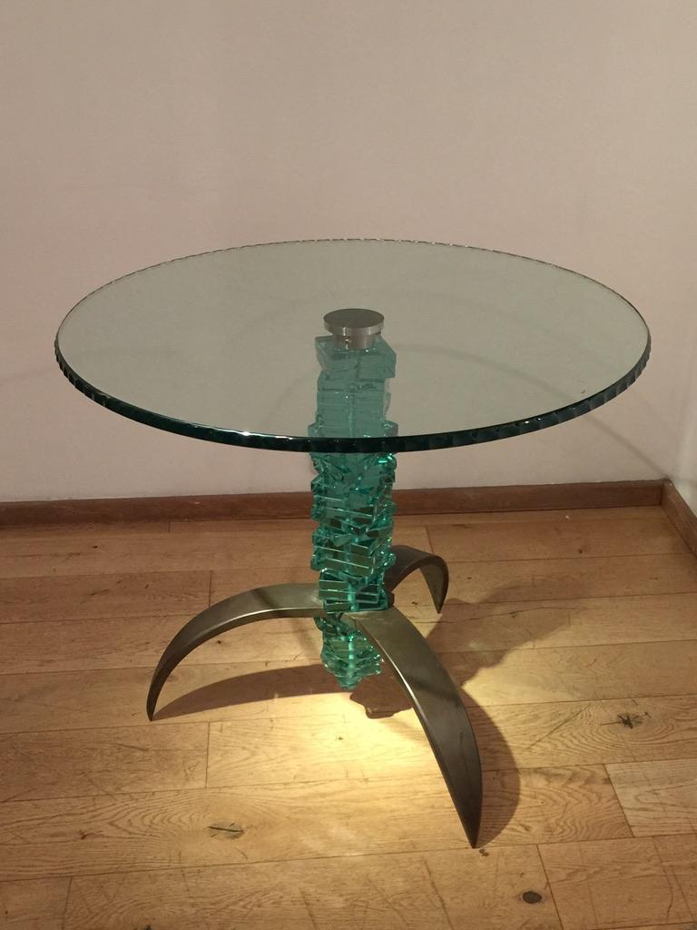 Danny Lane's signature 'stacked glass' forms the pedestal to this striking occasional table. The circular glass top has been hand 'chipped' with softened edges, and the feet are three curved straps of steel.