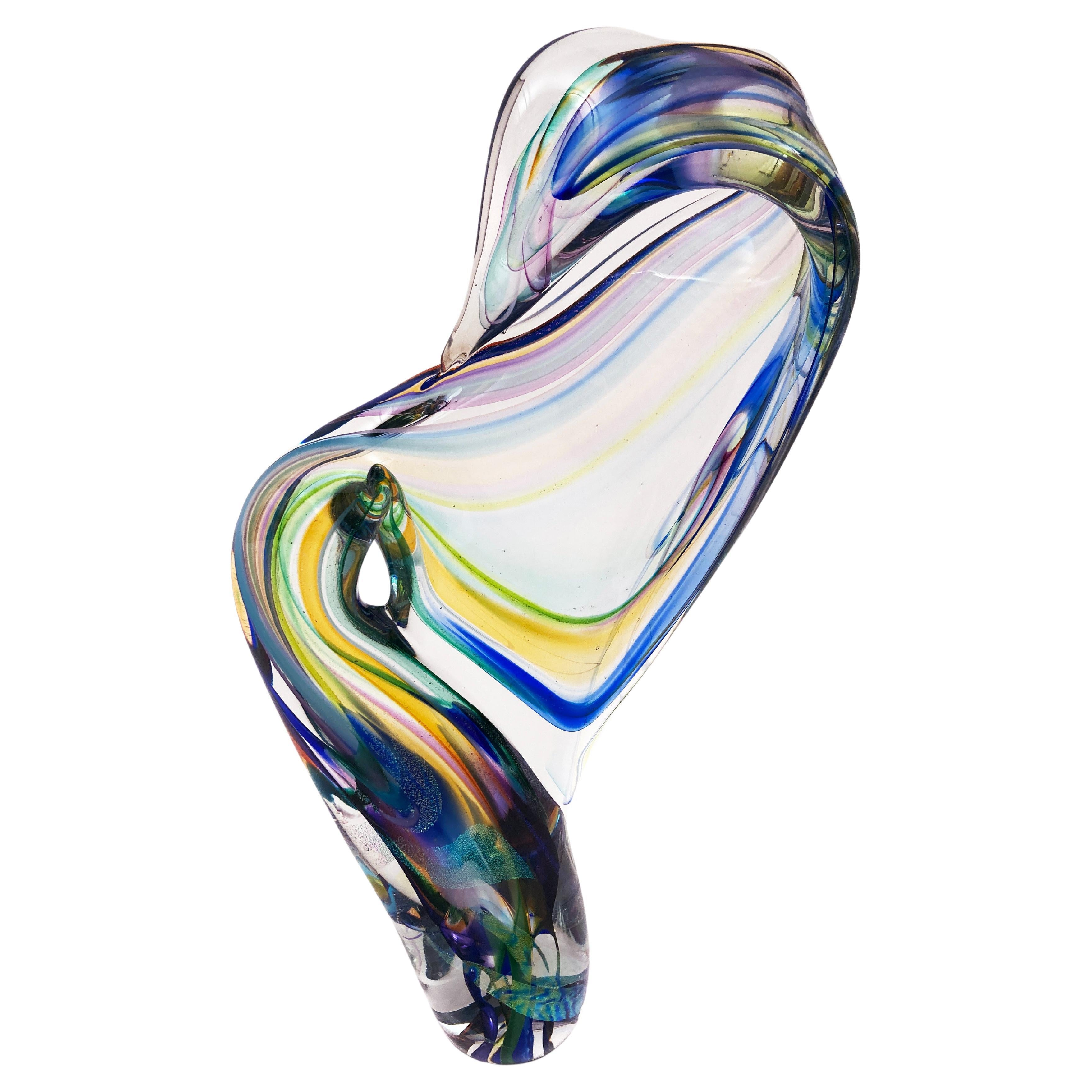 Cette étonnante sculpture en verre soufflé à la main, signée par Goldhagen, utilise une palette de couleurs froides et audacieuses avec des accents de teintes plus chaudes. Goldhagen, dans son génie créatif, crée un design fluide qui nous donne