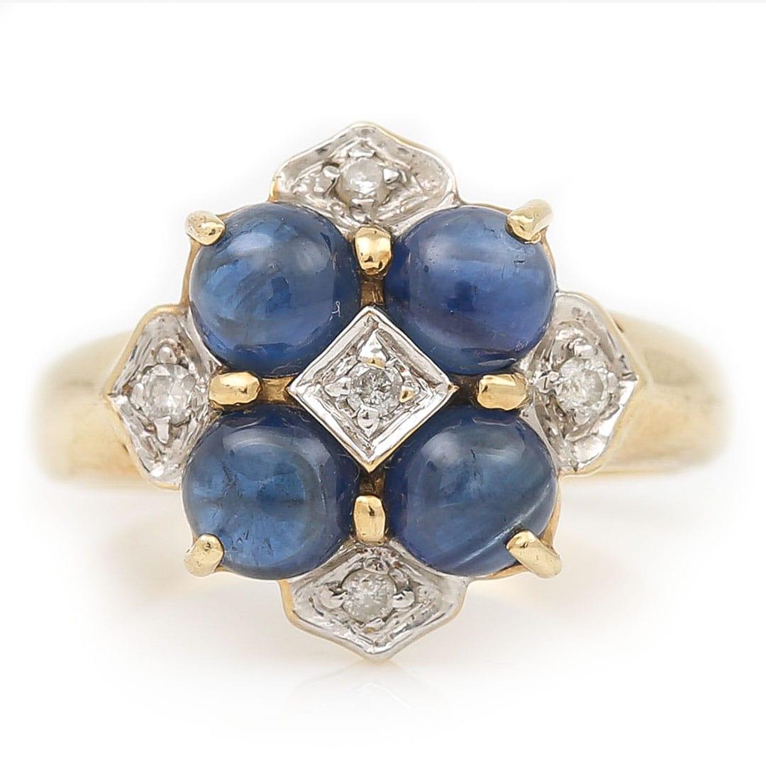 A contemporary statement ring with 4 deep blue cabochon cut sapphires surrounded by small brilliant cut diamonds all set in 9ct yellow gold. The elegant design of the ring makes it perfect for everyday wear or great for stacking with other rings.