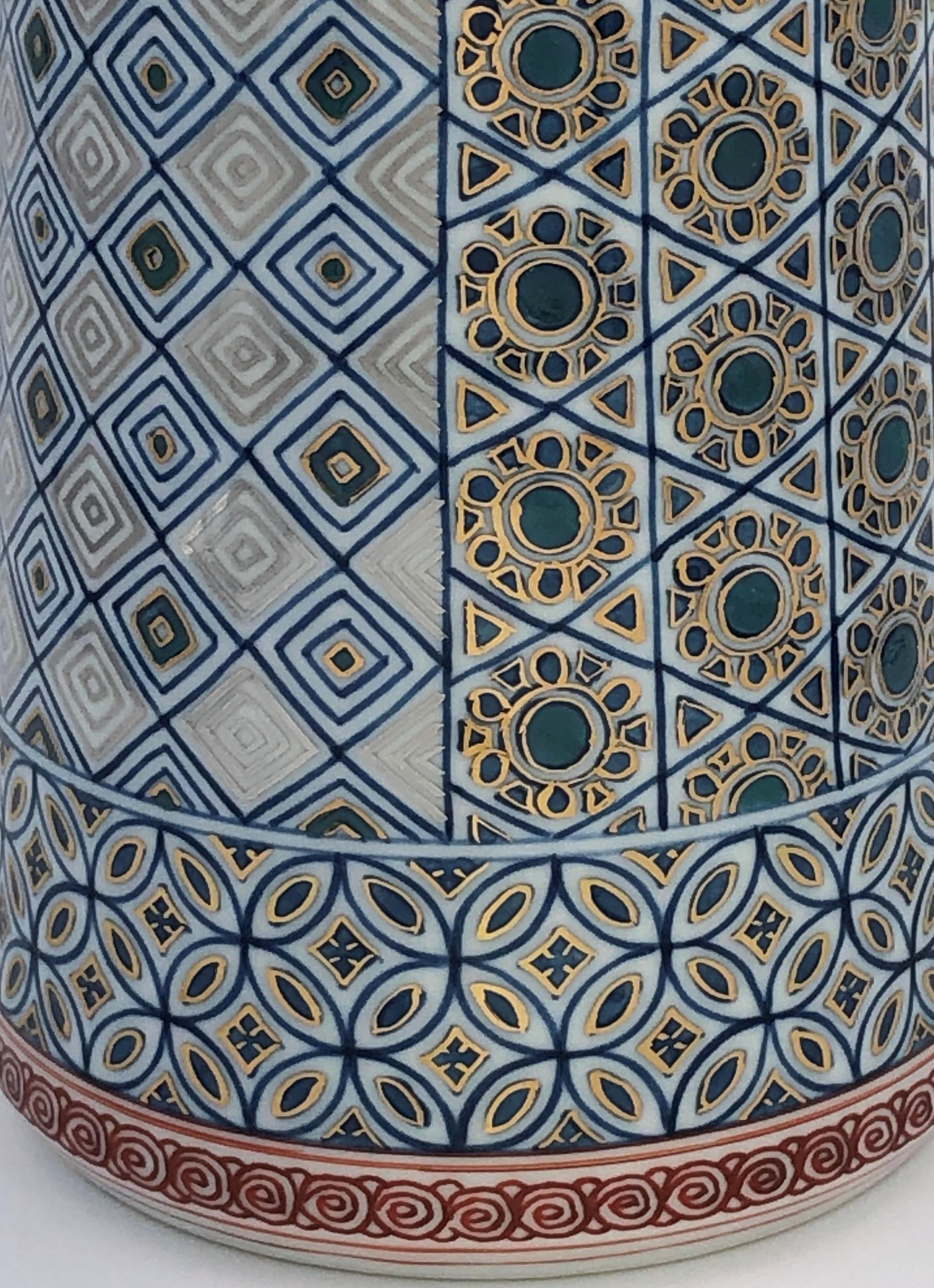 Mesmerizing Japanese decorative porcelain vase featuring a number of the artist's signature geometric patterns extremely intricately hand painted in the artist's signature miniature technique in deep underglaze blue and generous gold details, set