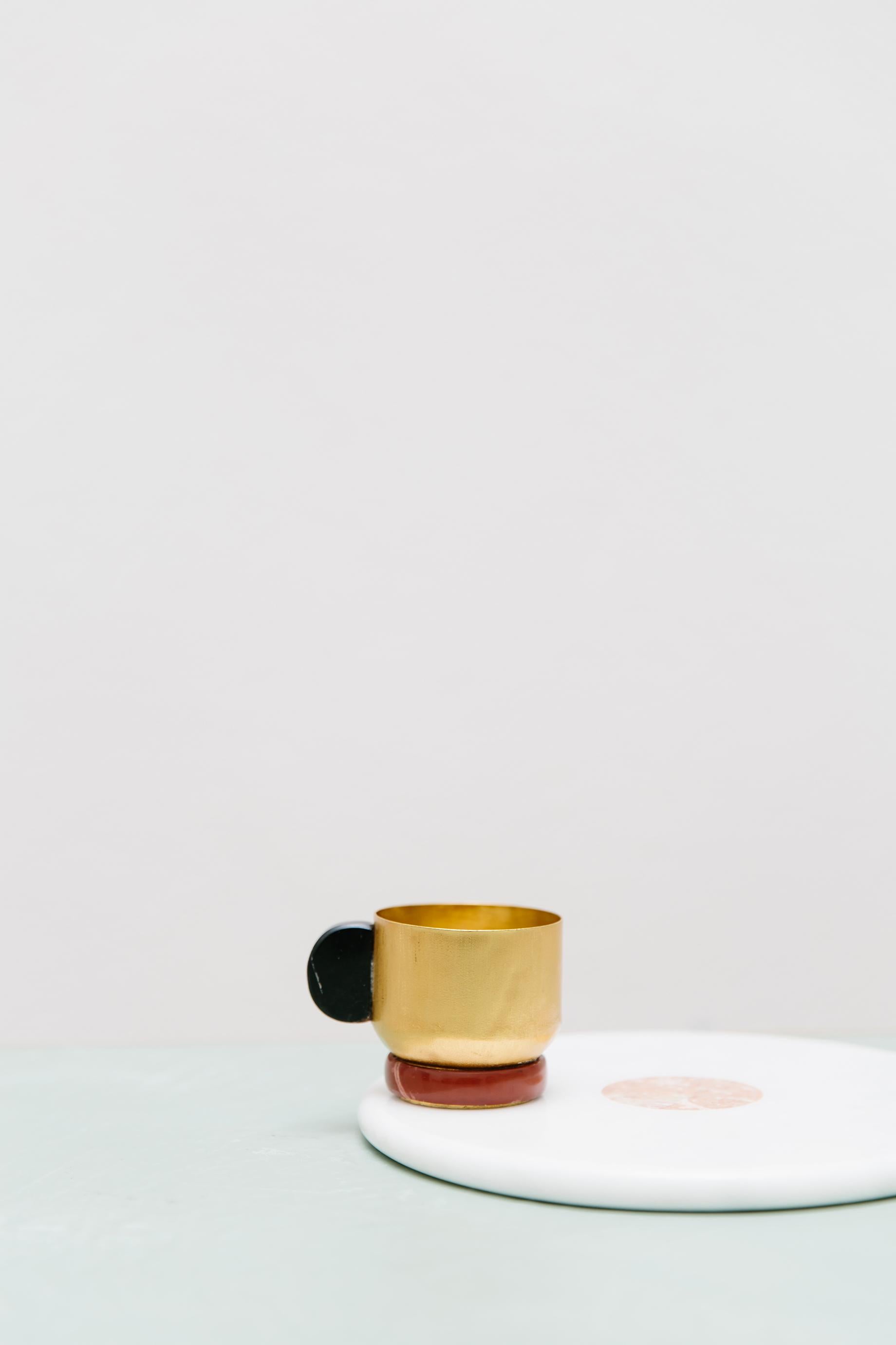 Werten Sie Ihr tägliches Tee- oder Kaffeeritual mit unserer exquisiten Onix-Tasse auf. Der Becher aus vergoldetem Messing wird in Italien mit Hilfe von Blechdrehtechniken handgefertigt. Der mit einem Onix-Stein verzierte Griff verleiht Ihrem