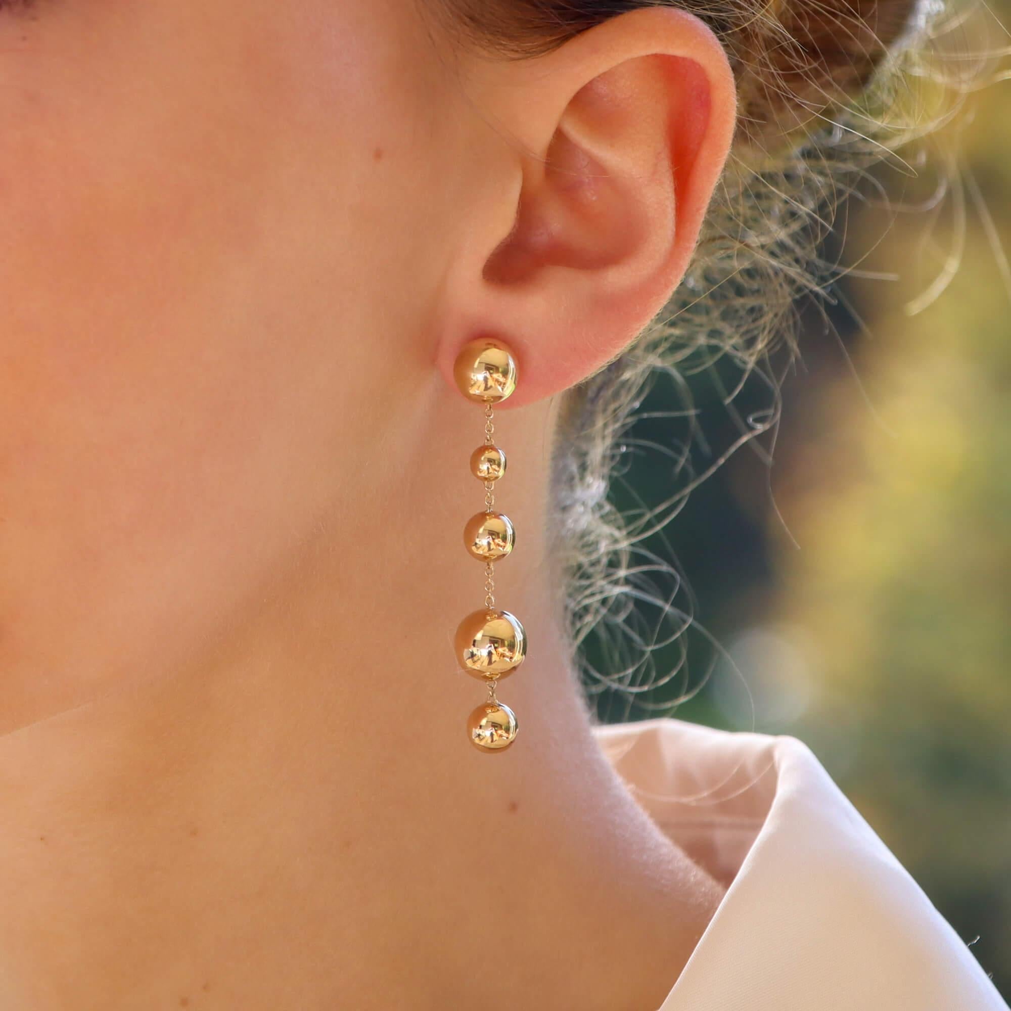 A stylish pair of contemporary drop earrings set in 18k yellow gold.

Each earring is composed of five different sized yellow gold polished balls, connected together via a simple trace chain. They are secured with a post and butterfly fitting.

Due