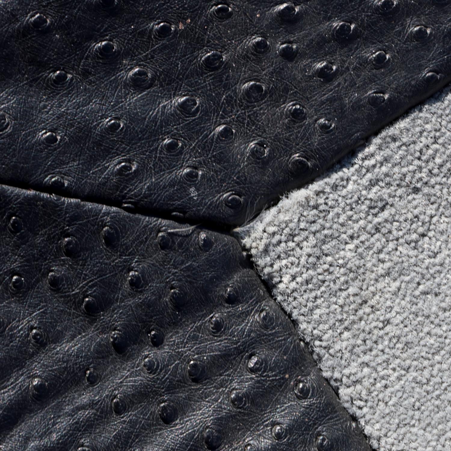 Un tappeto personalizzato contemporaneo caratterizzato da un raffinato gioco di texture e toni. Questo sofisticato rivestimento per pavimenti è realizzato in un morbido tessuto grigio a basso pelo con un lussuoso bordo in pelle nera goffrata a