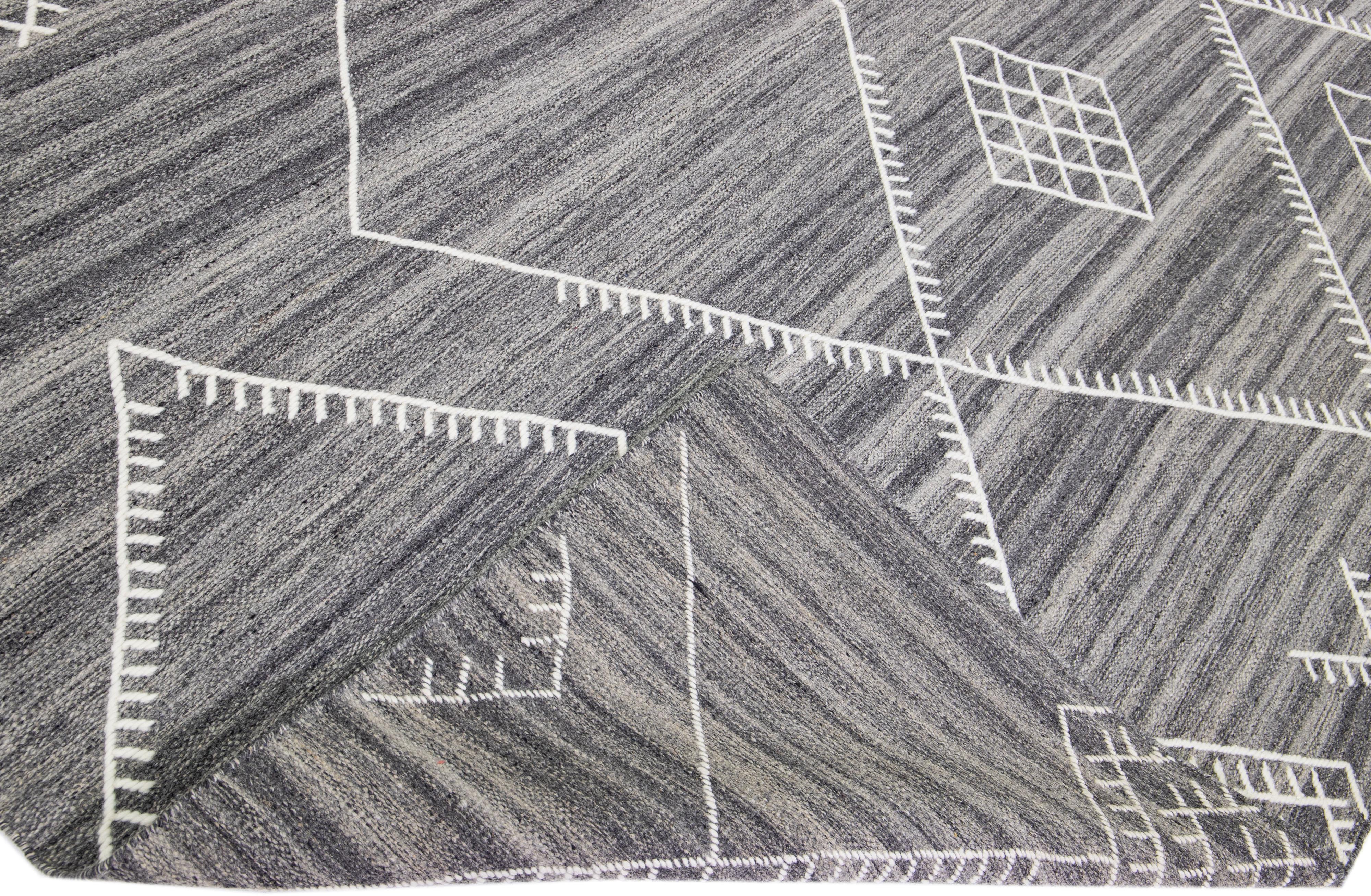 Schöner handgefertigter Kelimteppich aus Wolle mit grauem Feld. Dieser moderne Flachgewebe-Teppich aus unserer Nantucket-Kollektion hat weiße Akzente und ein wunderschönes, geometrisches Küstendesign.

Dieser Teppich misst: 12'6
